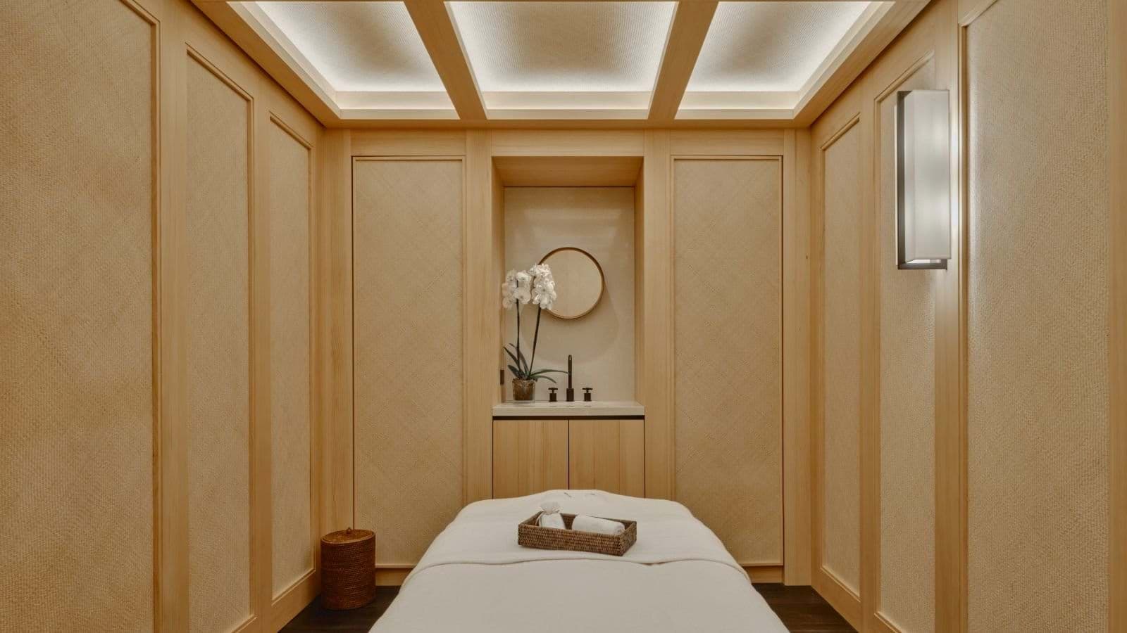 Private spa room with massage table, vanity, and ambient coffered lighting