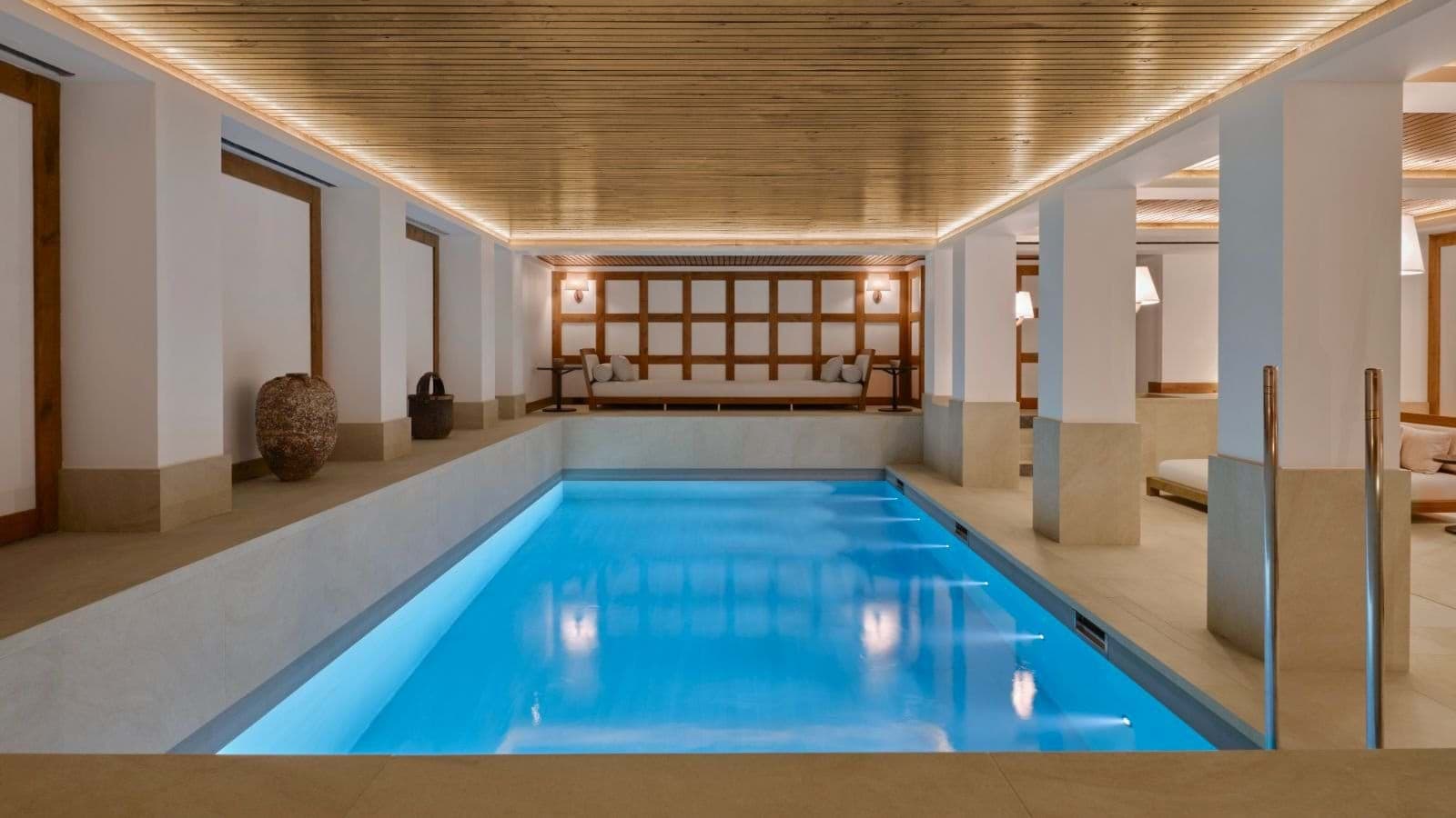 Indoor pool with underwater lighting and adjacent poolside daybeds
