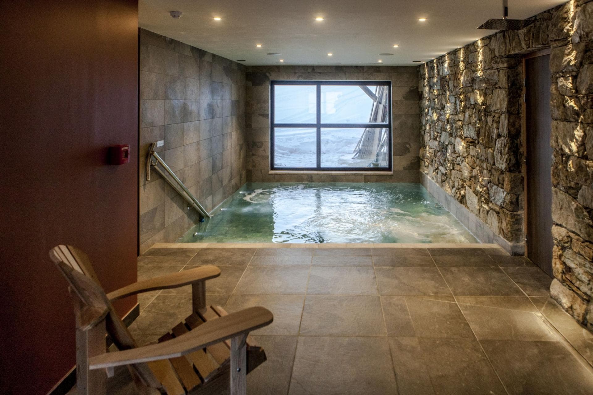 Indoor heated pool with stone feature wall and snow-covered mountain views