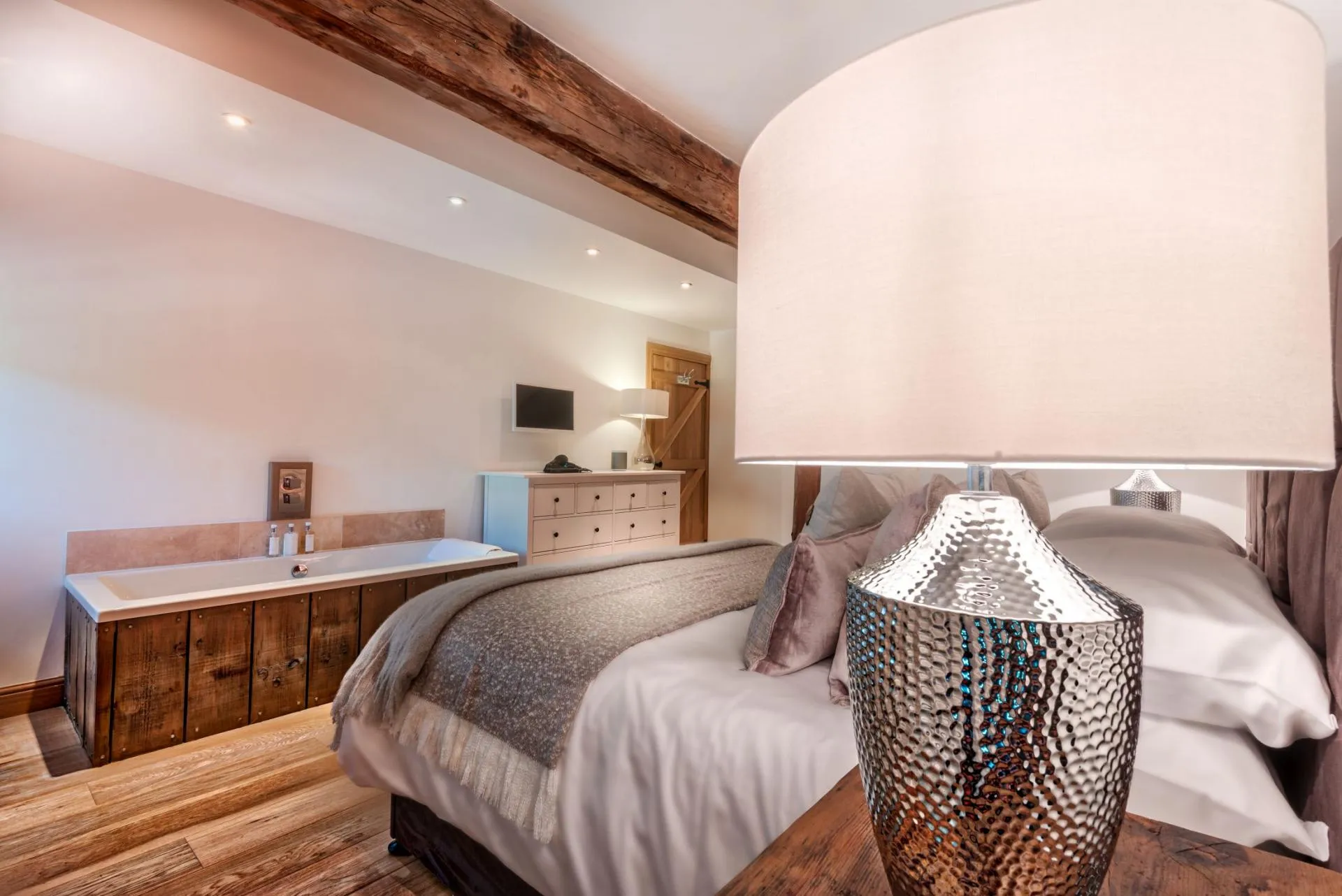 Primary bedroom with in-room soaking tub and original wood beams