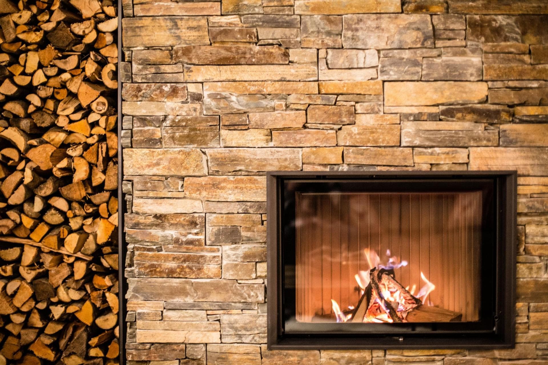 Wood-burning fireplace with stone surround and integrated firewood storage