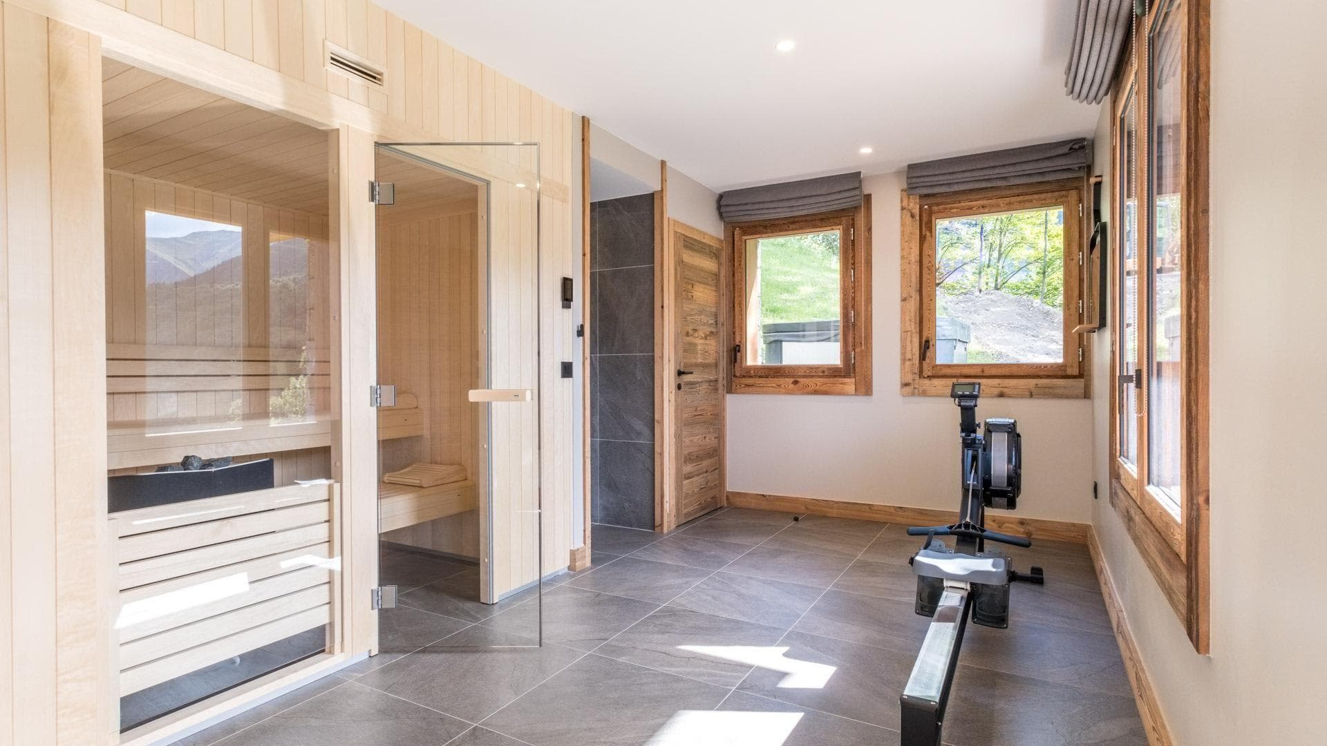Private wellness room with glass-fronted sauna and Concept2 rowing machine