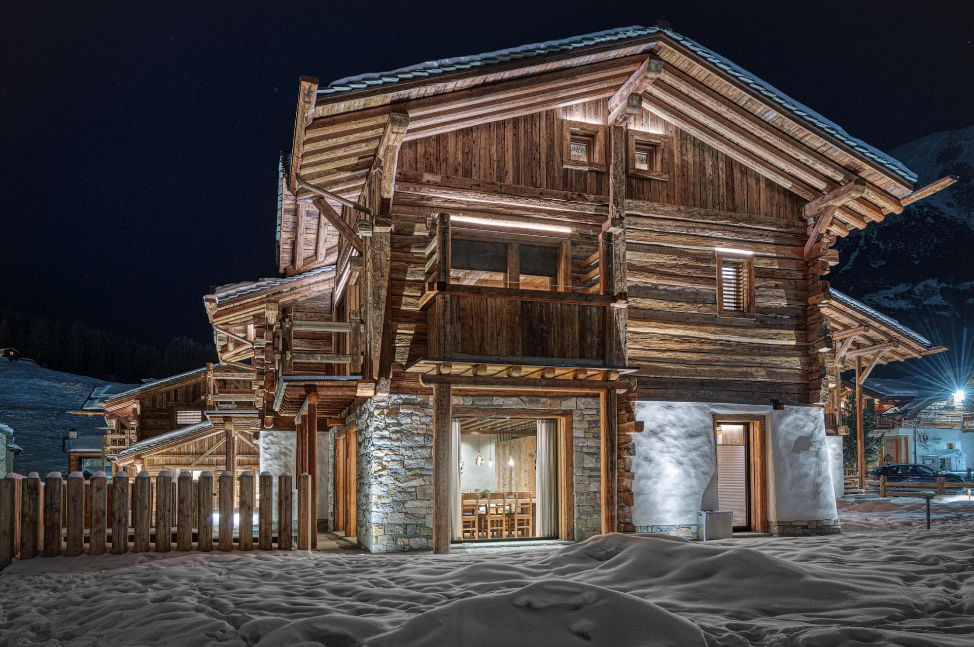 Chalet exterior at night with illuminated dining area and private balconies