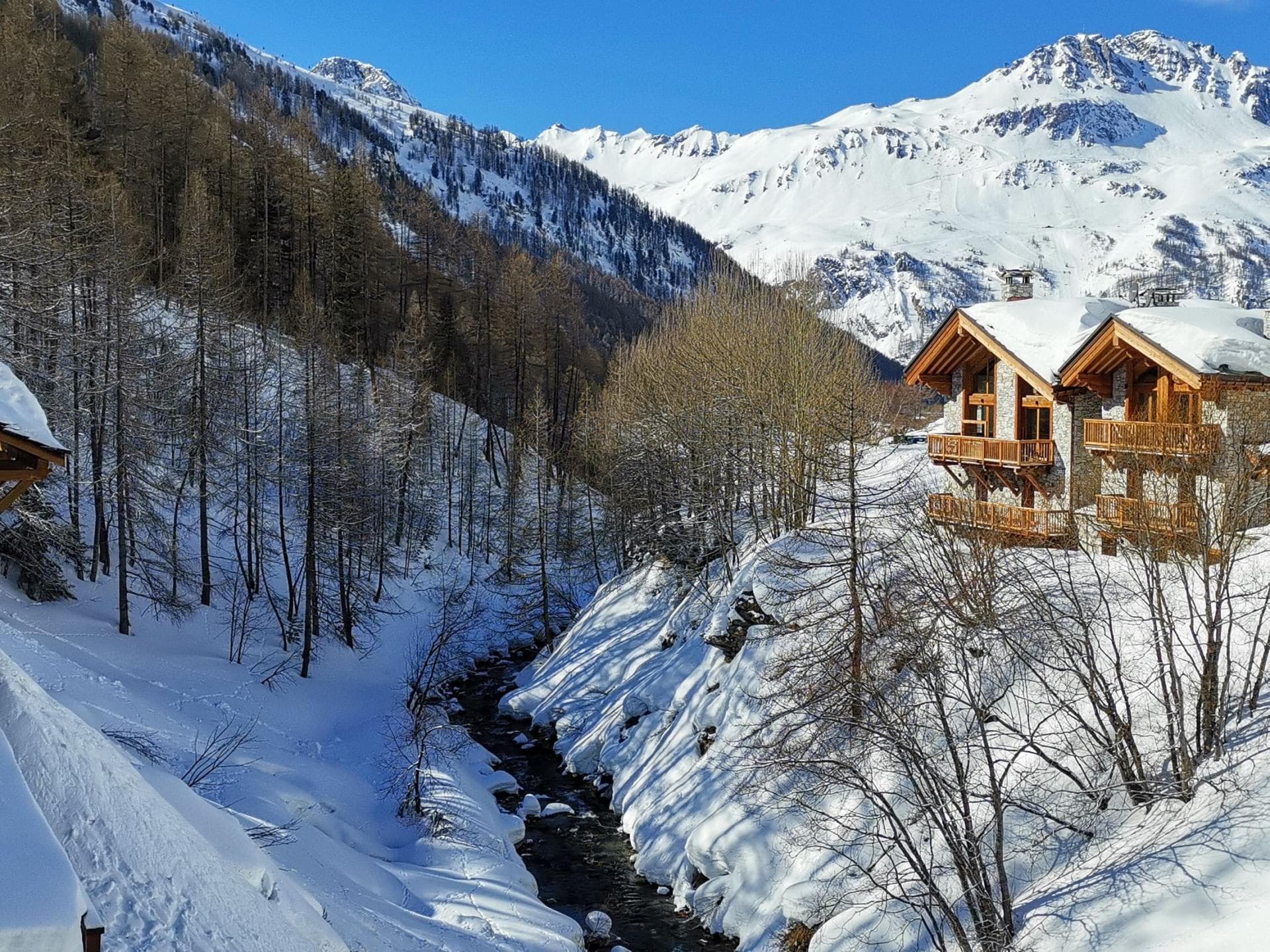Chalet exterior featuring private balconies and stream-side location with mountain views