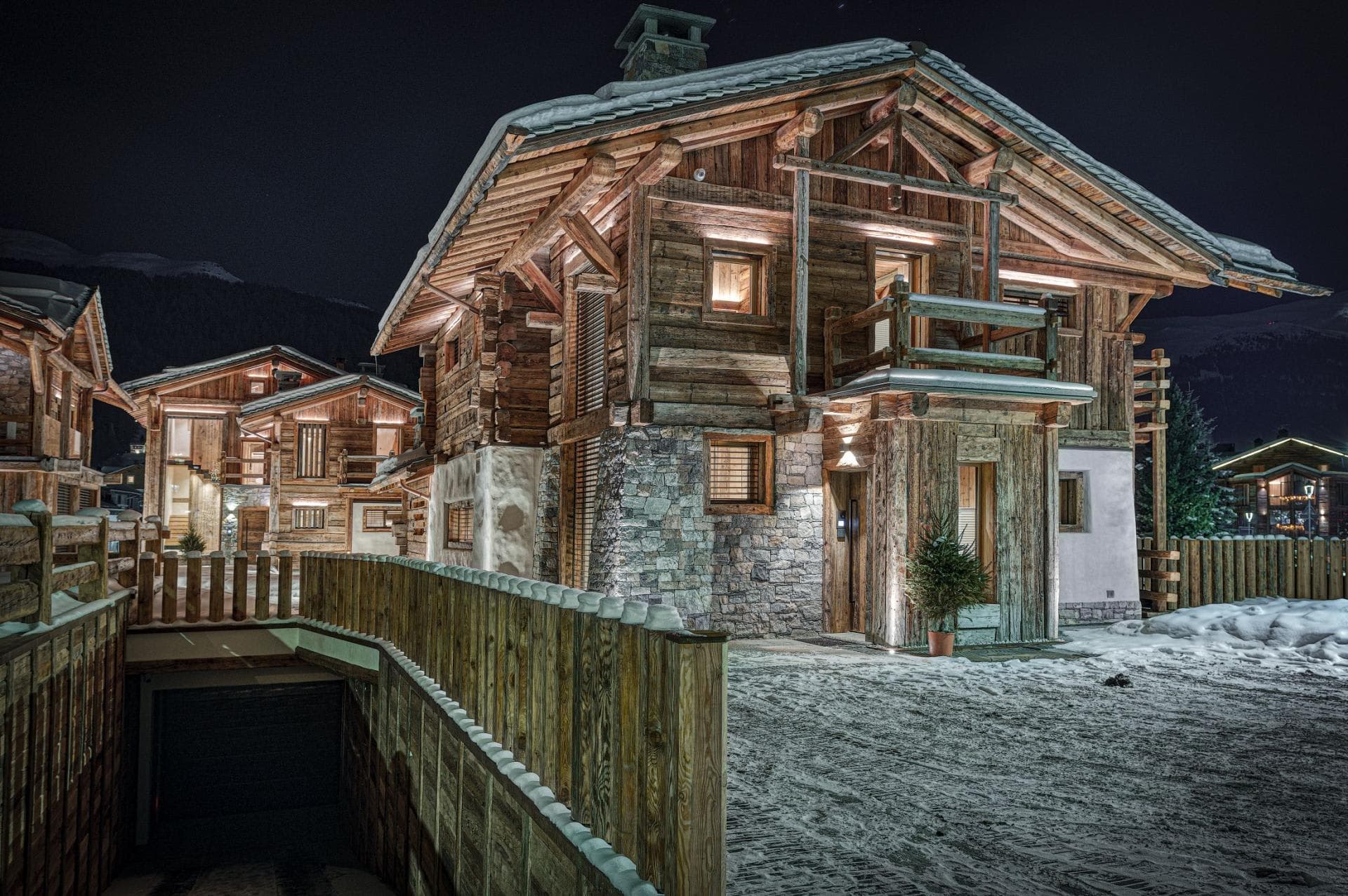 Chalet exterior at night with timber facade and underground parking garage