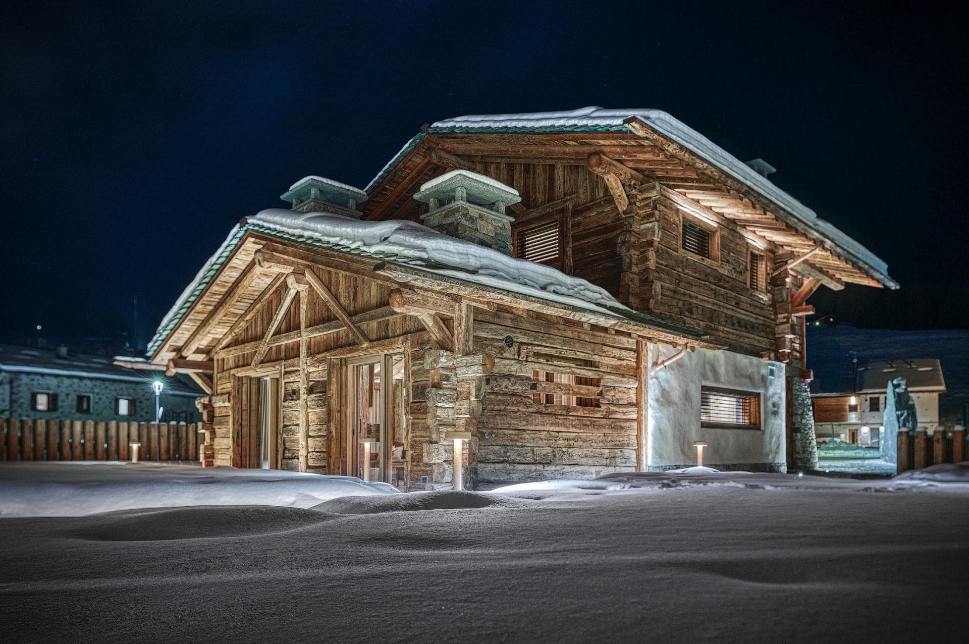 Timber chalet exterior featuring hand-hewn logs and stone chimneys