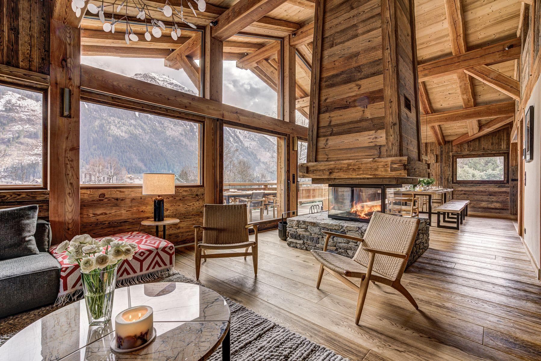 Living area with 360-degree glass fireplace and floor-to-ceiling mountain views