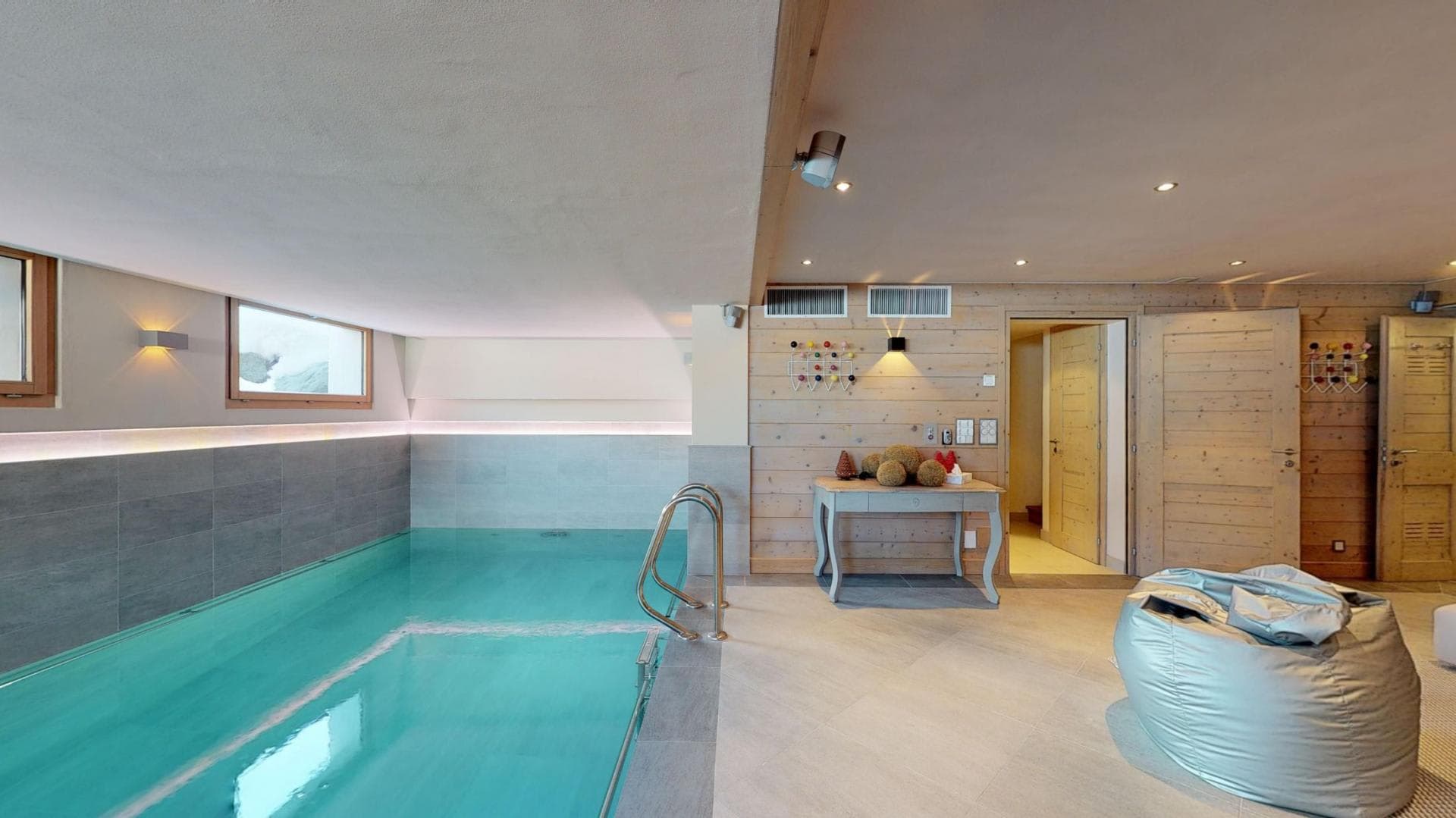 Indoor heated pool with ladder access and adjacent lounge area