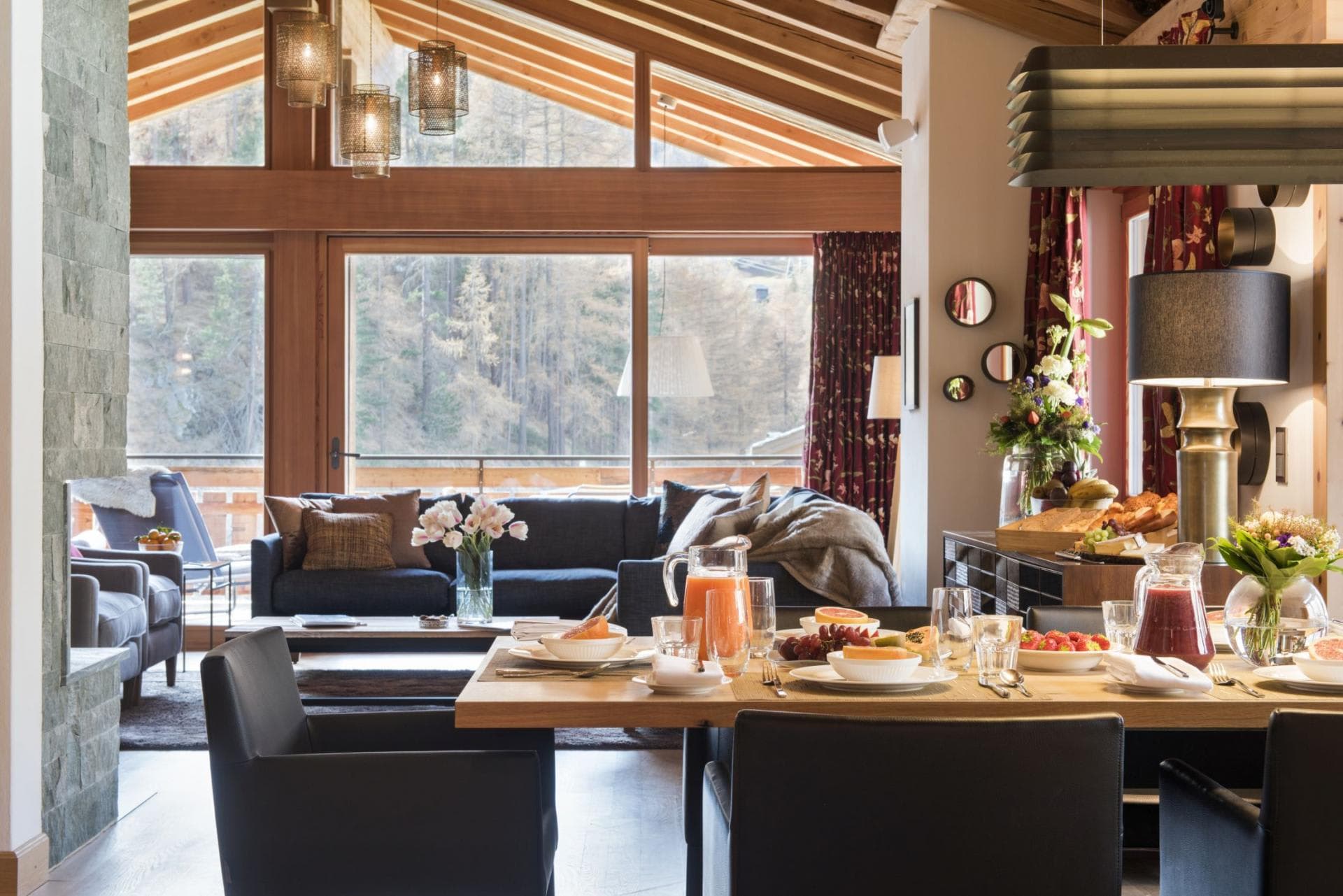 Open-plan dining and living area with forest views and fireplace