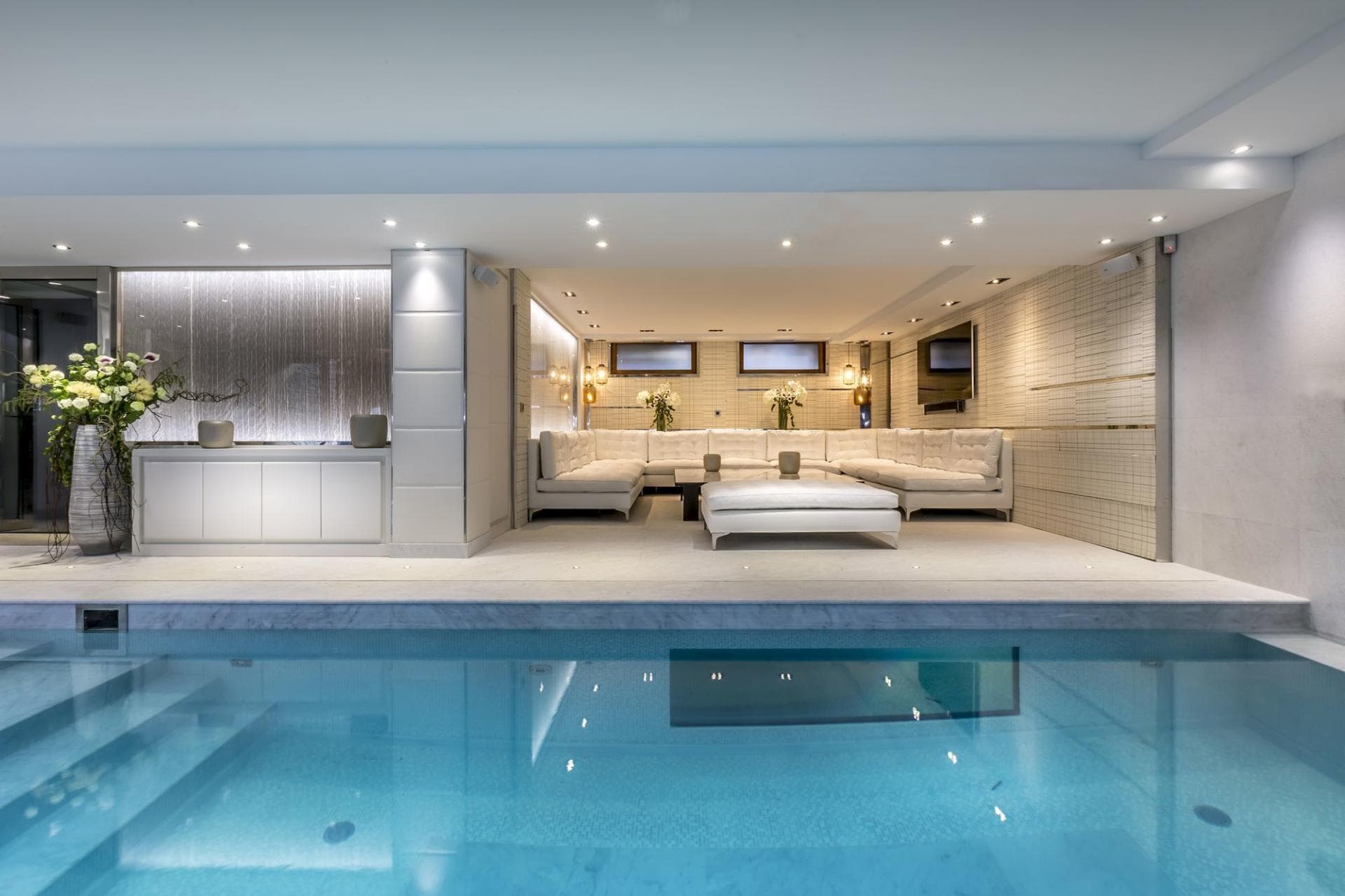 Indoor pool with integrated lounge and textured glass water feature