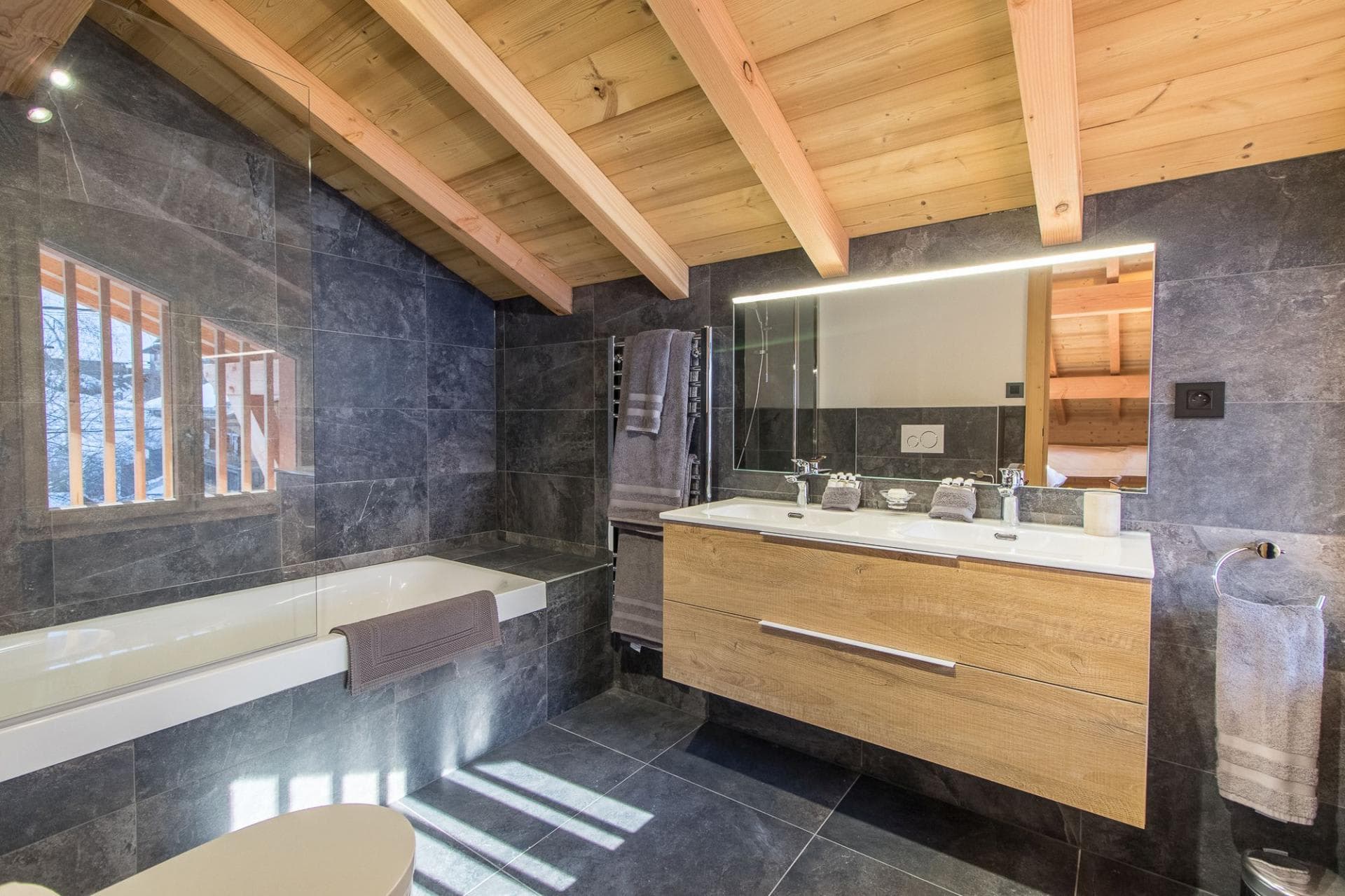 Bathroom with dual vanity, soaking tub, and heated towel rack