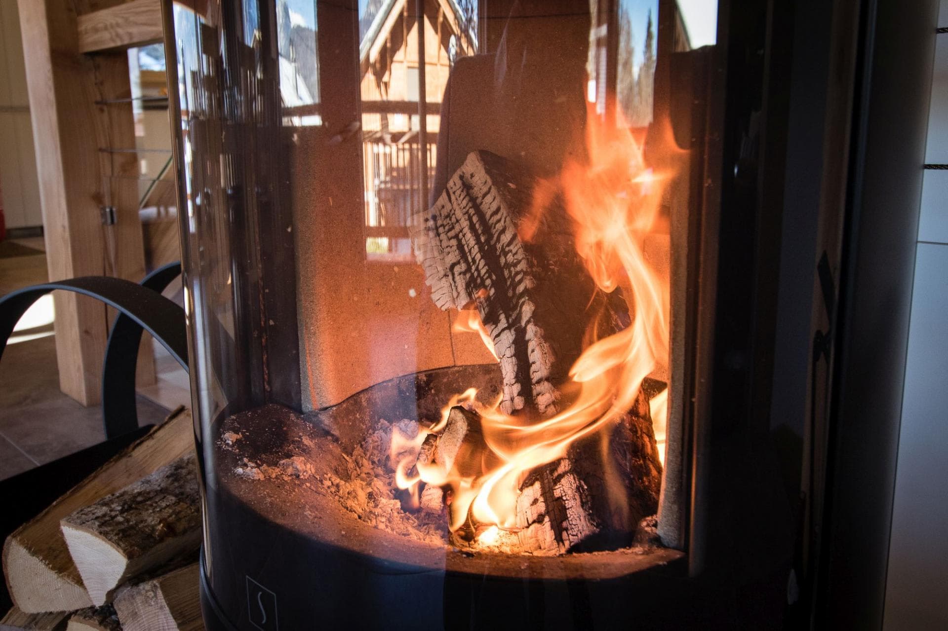 Cylindrical wood-burning stove with curved glass and log storage