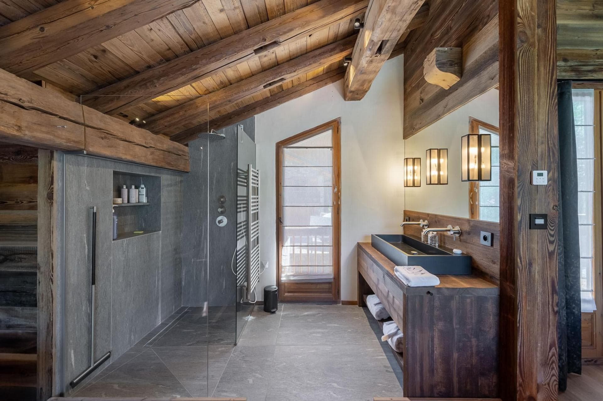 Bathroom with walk-in rain shower, heated towel rack, and stone finishes