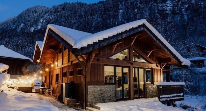 Chalet exterior with private hot tub under string lights; mountain backdrop