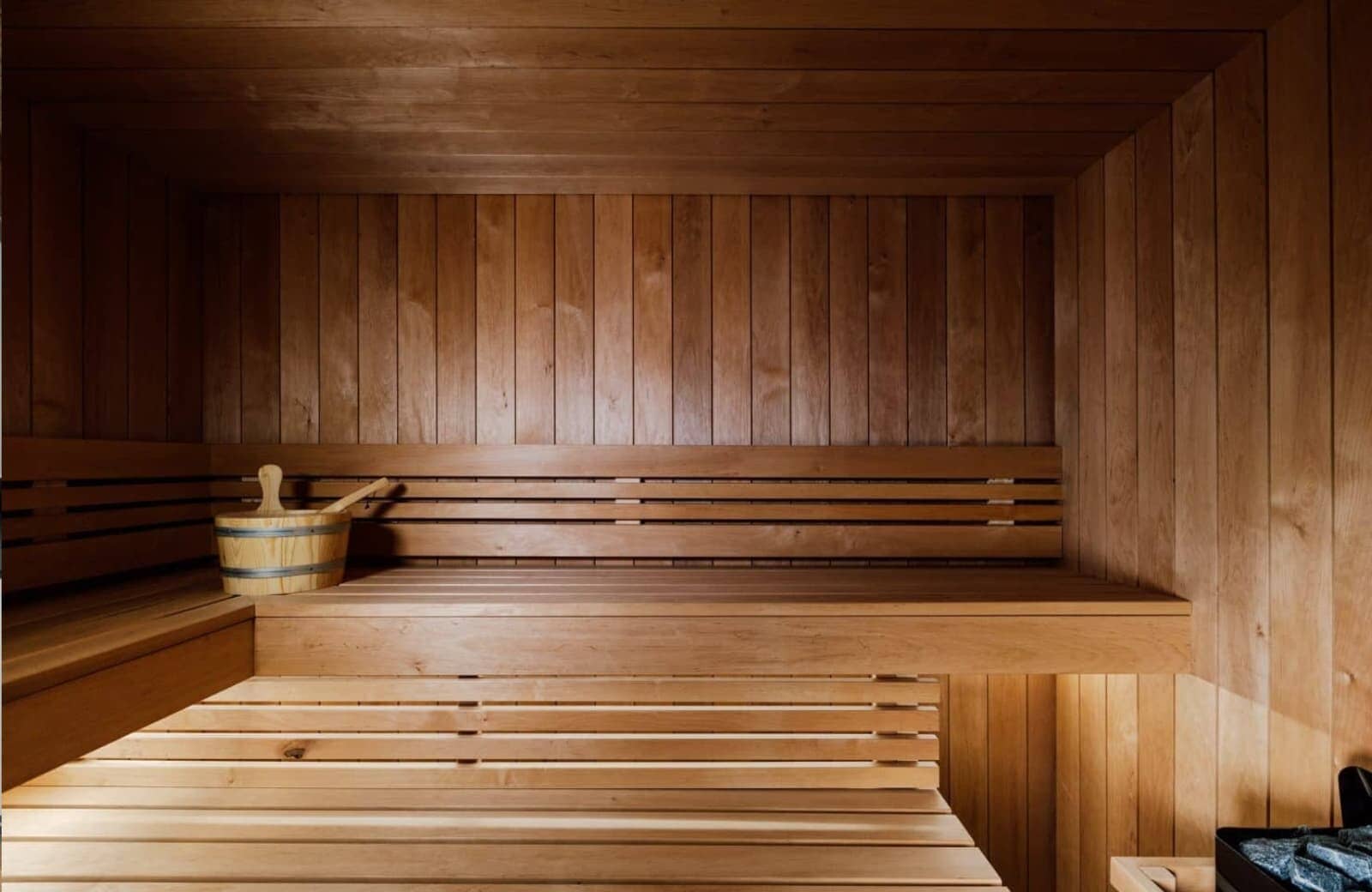 Wood-paneled sauna with tiered bench seating and traditional bucket