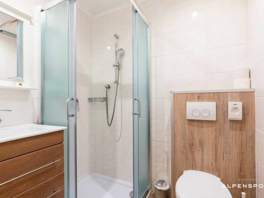 Bathroom with walk-in corner shower, vanity storage, and handheld showerhead