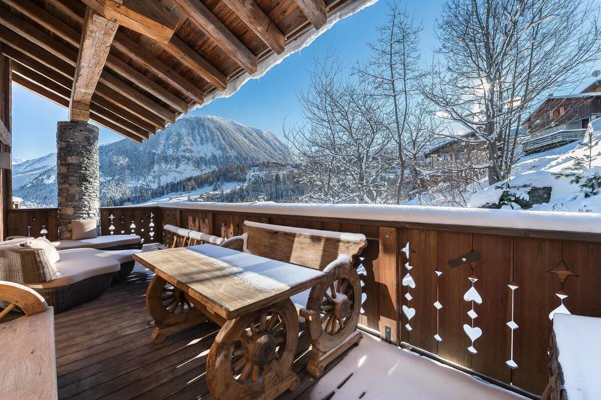 Covered balcony with mountain views, lounge seating, and hand-carved wood table