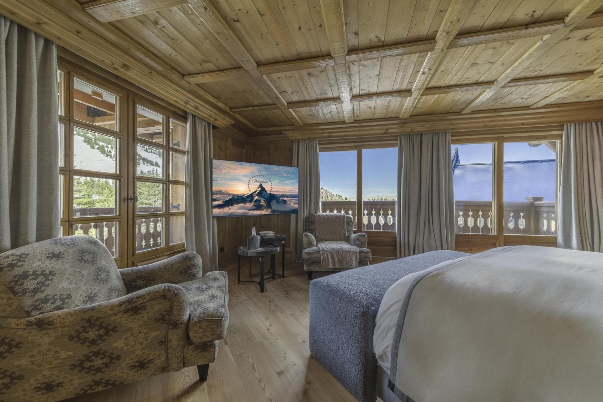 Wood-paneled bedroom with king bed and mountain-view balcony