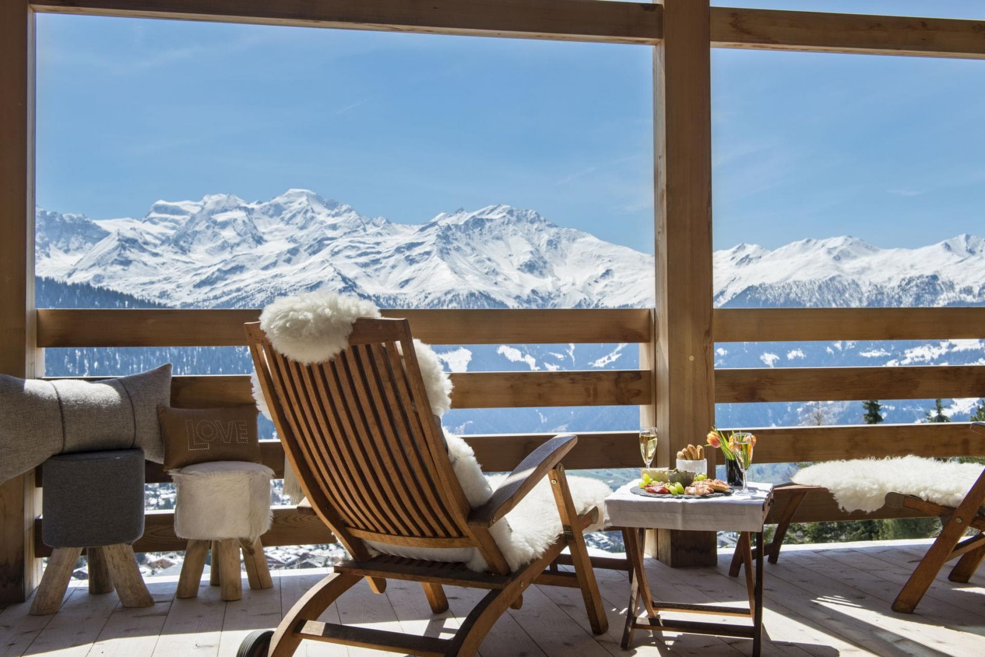 Private balcony with wooden lounge chairs and panoramic Alps view