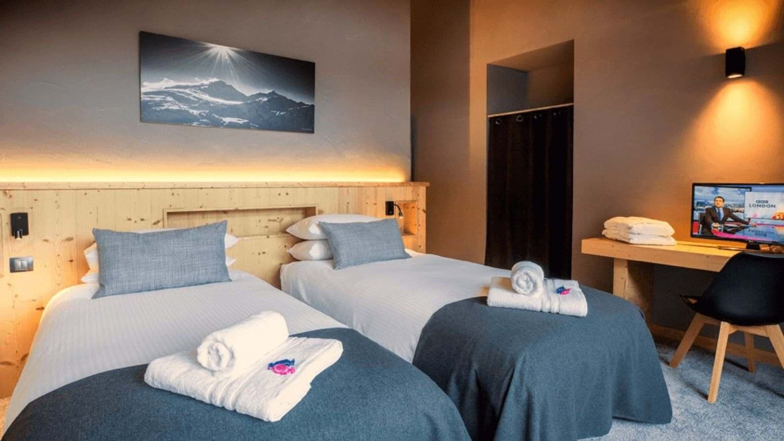 Guest bedroom with two twin beds and dedicated workspace with TV