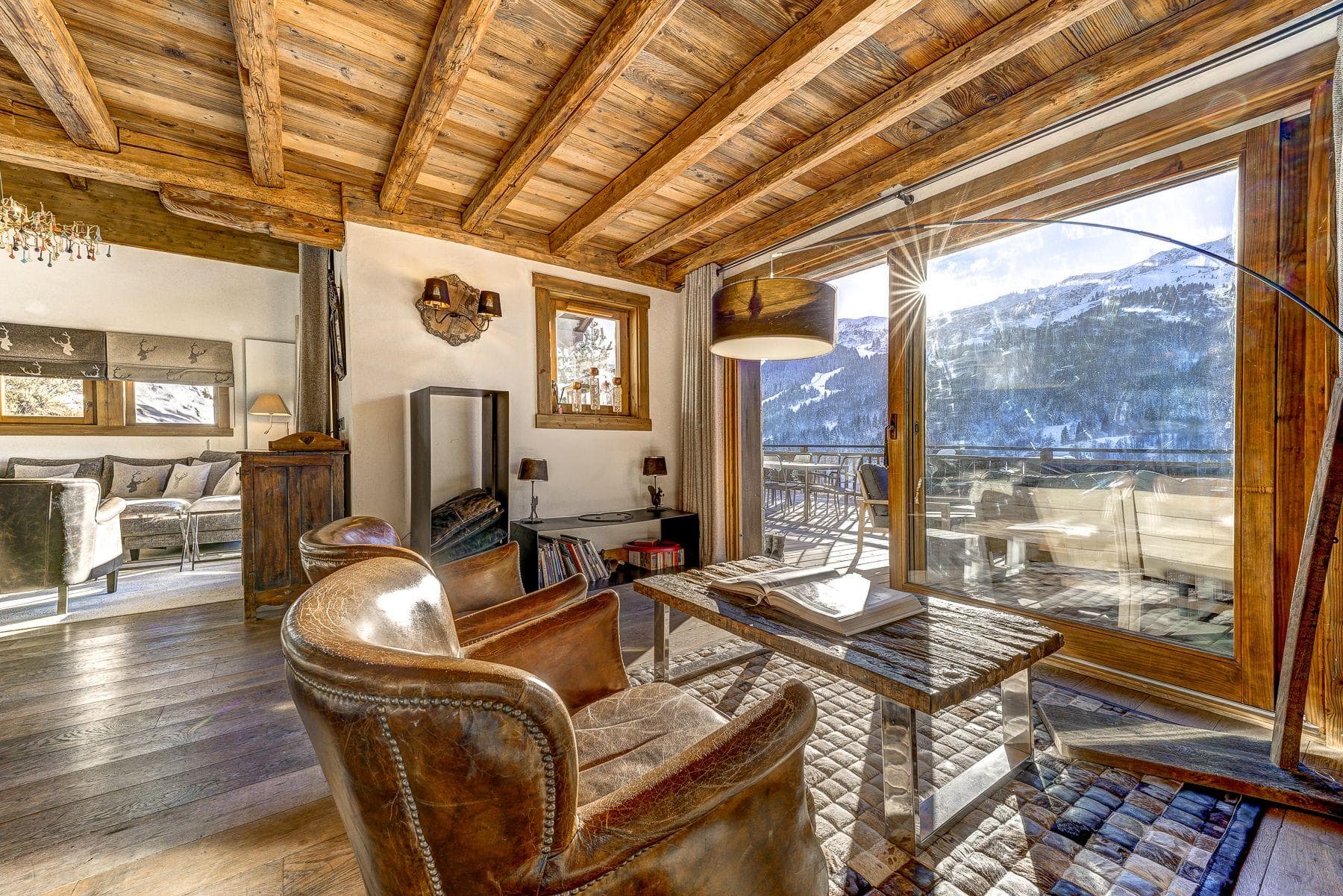 Seating area with leather armchairs and sliding glass doors to mountain balcony