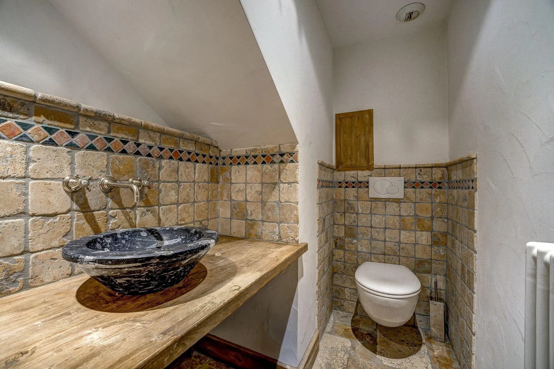 Powder room featuring marble vessel sink and wall-mounted toilet