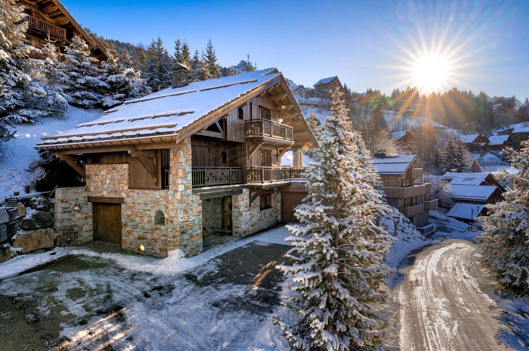 Chalet exterior with stone facade, wrap-around balconies, and driveway parking