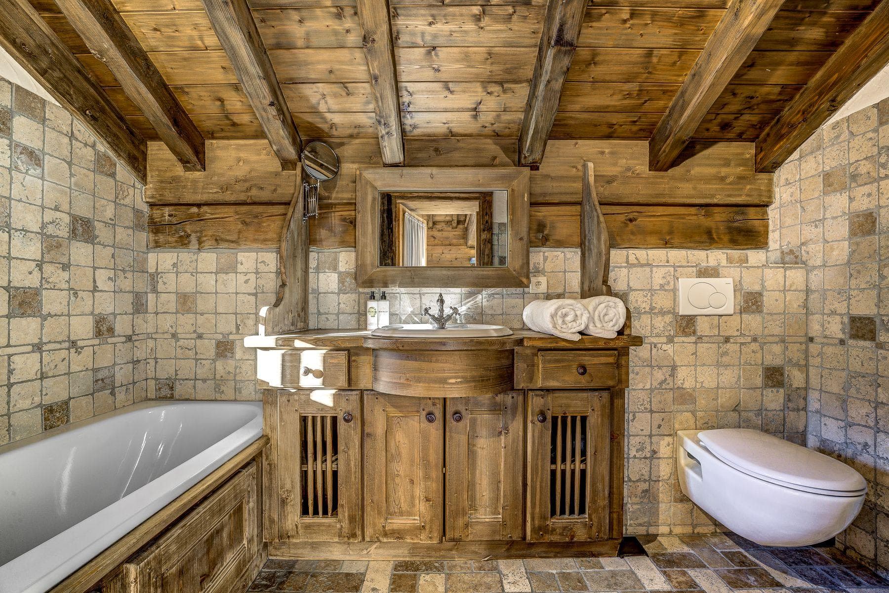 Bathroom with soaking tub, timber vanity, and rustic stone tile