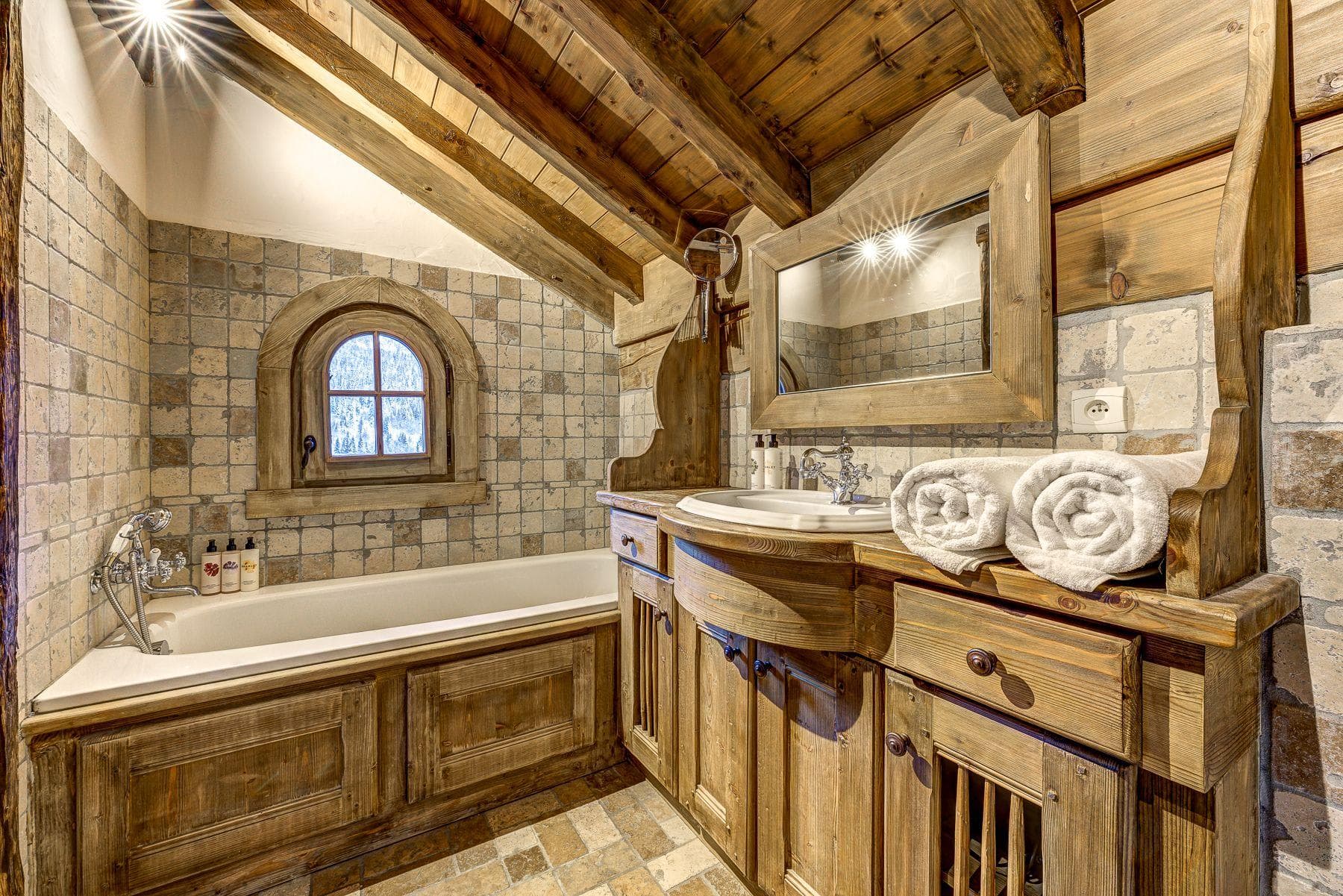 Bathroom with soaking tub, reclaimed wood vanity, and stone tile walls