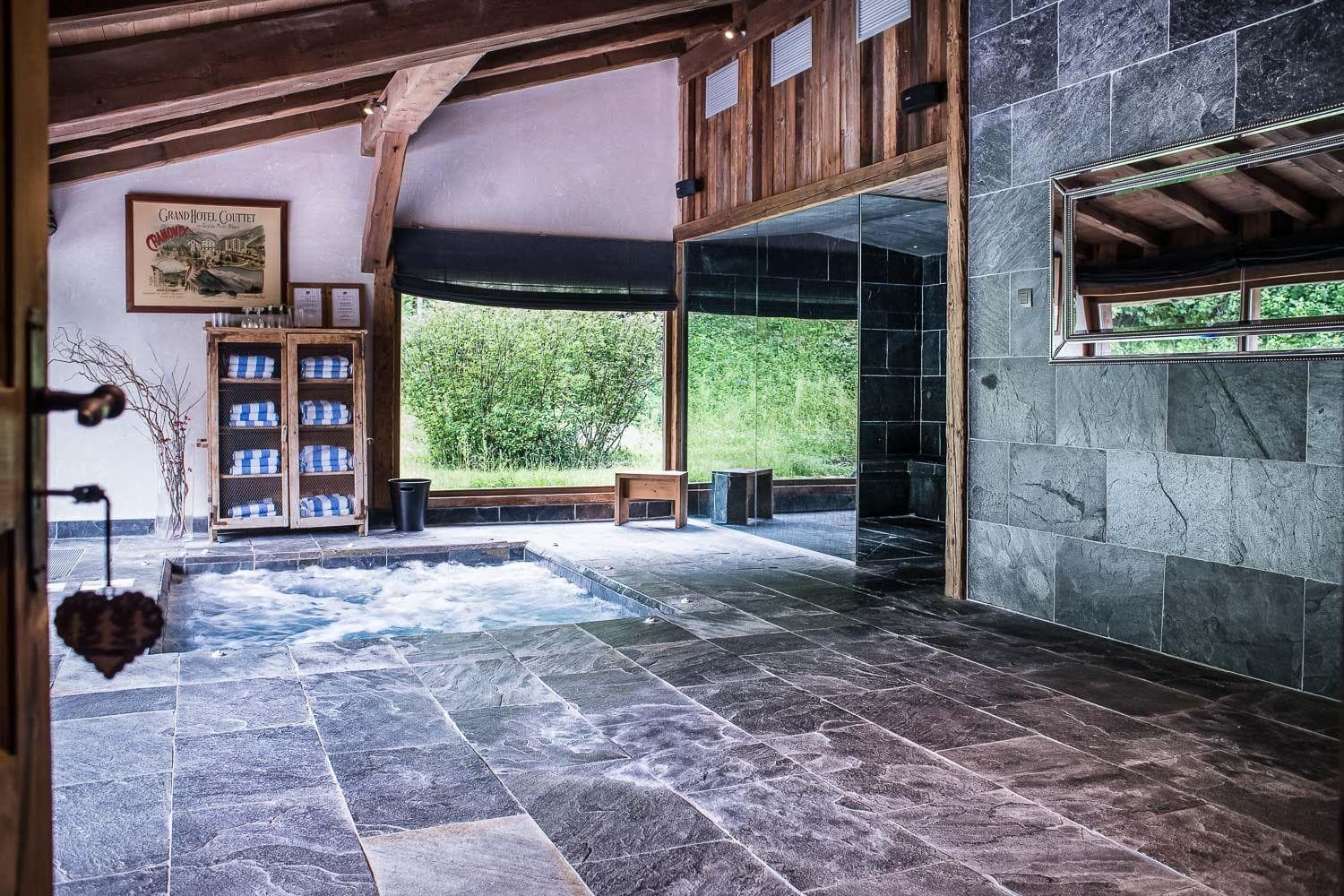 Indoor pool and spa area with slate tiling and adjacent steam room