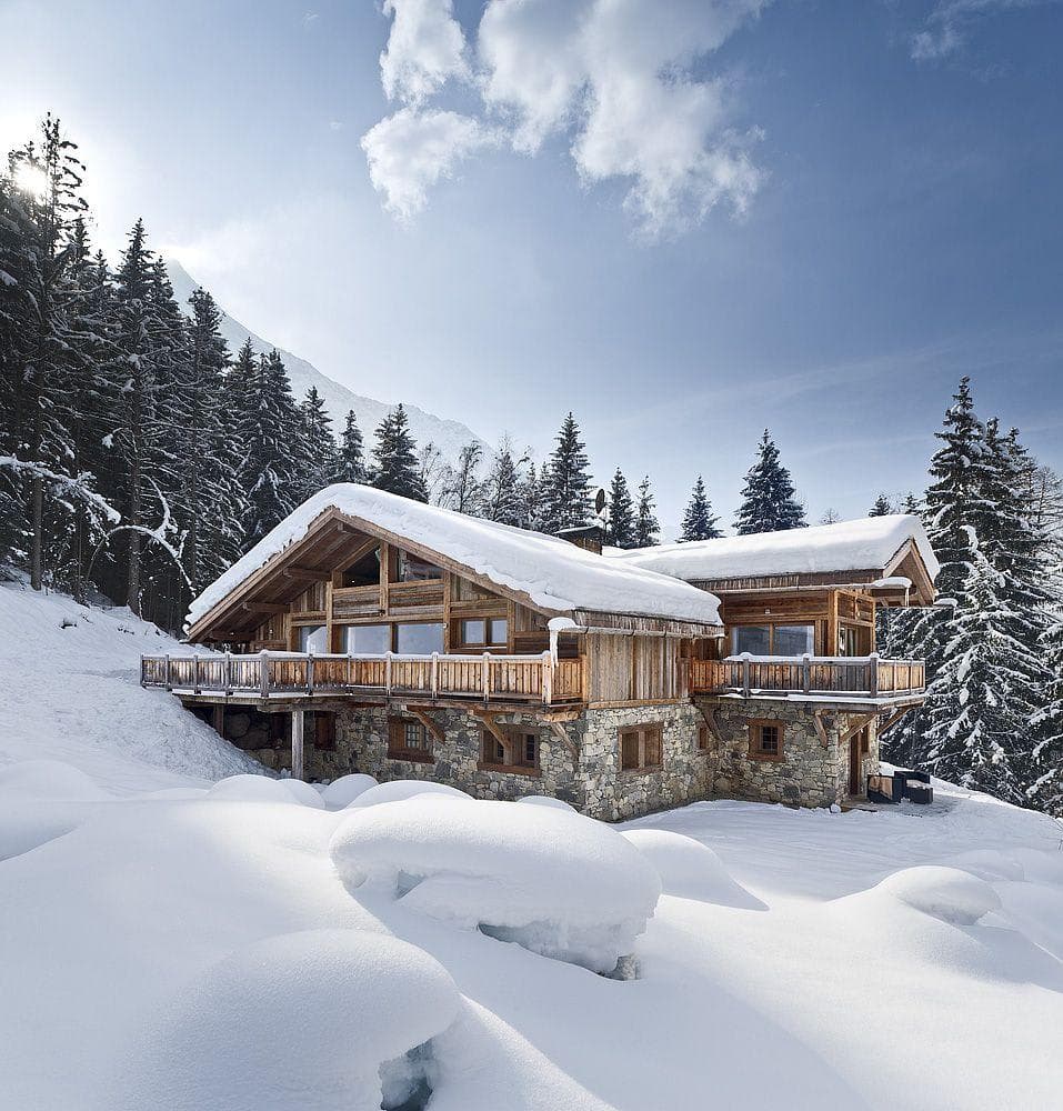 Ski-in chalet exterior with wrap-around deck and forest views