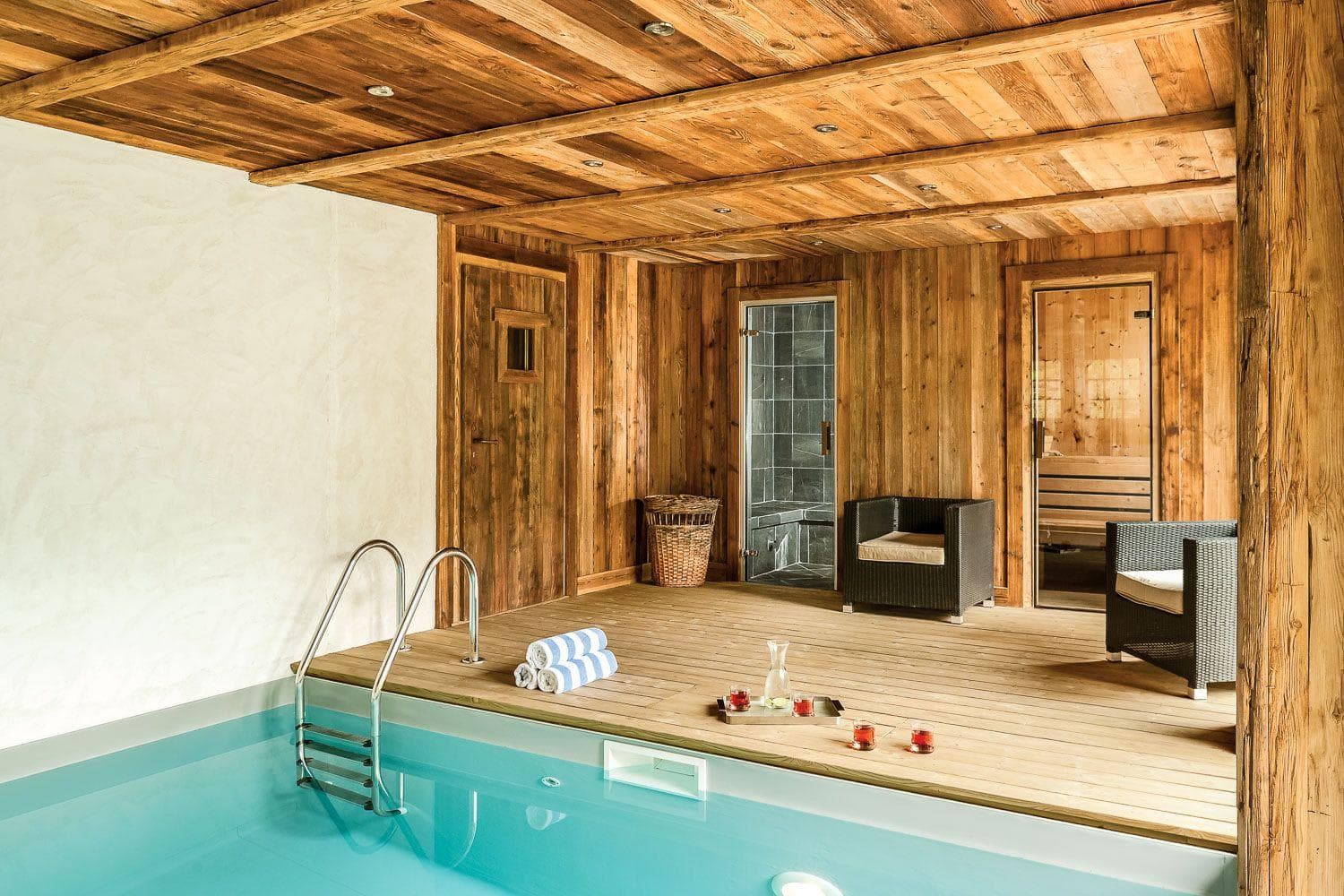 Indoor pool area with adjacent steam room and wood-paneled sauna