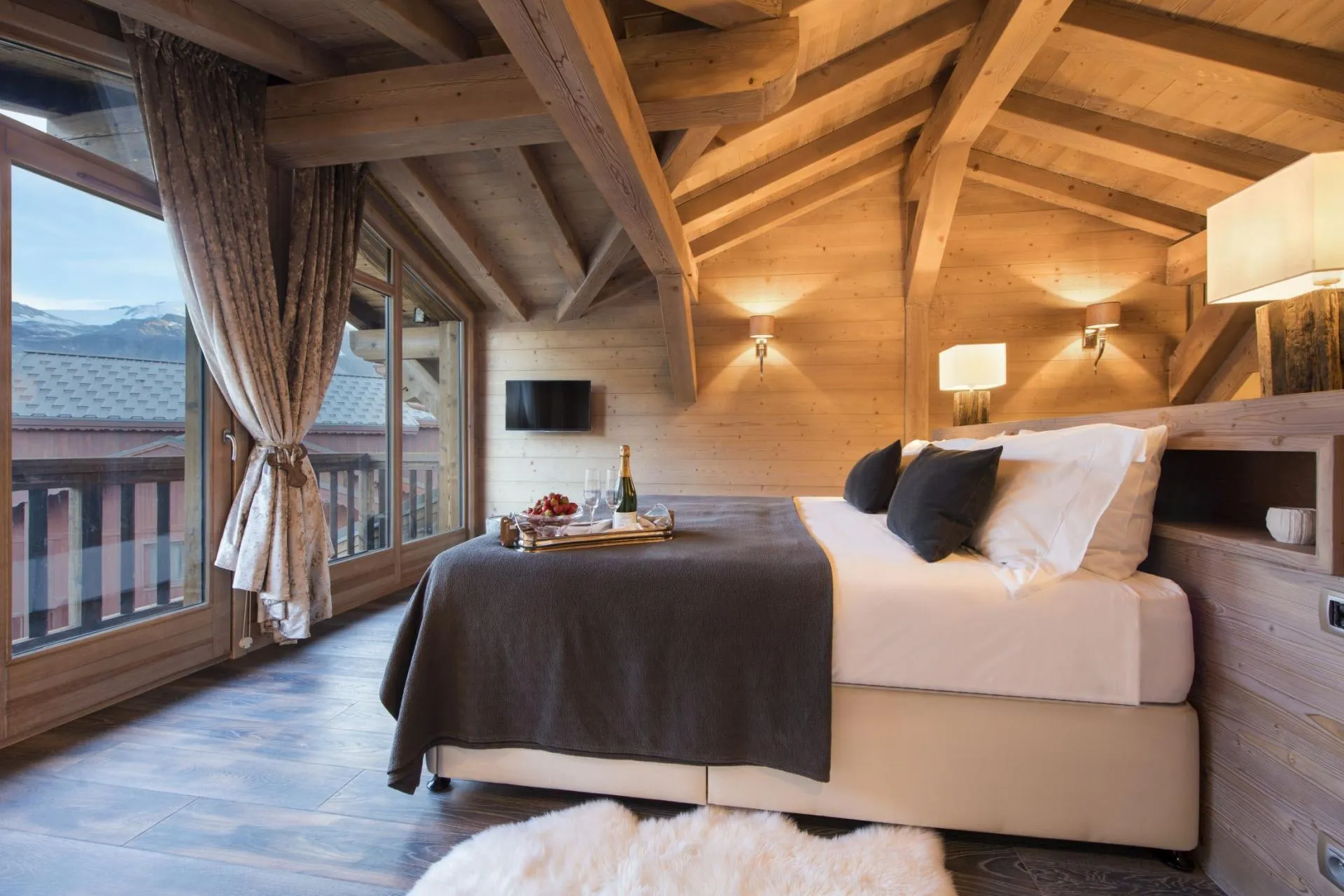 Top-floor bedroom with vaulted timber ceilings and private balcony access