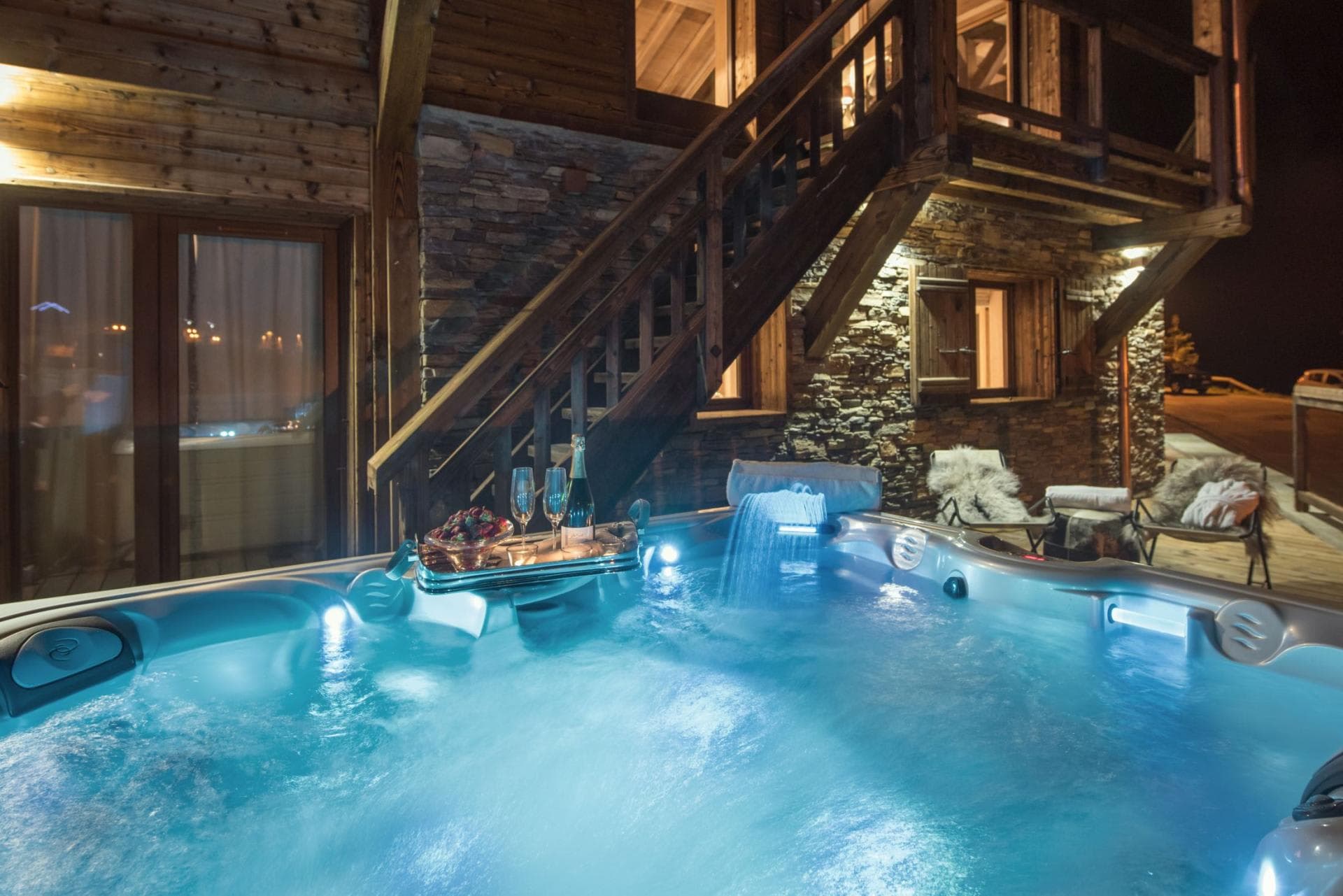 Outdoor hot tub with waterfall feature and illuminated seating