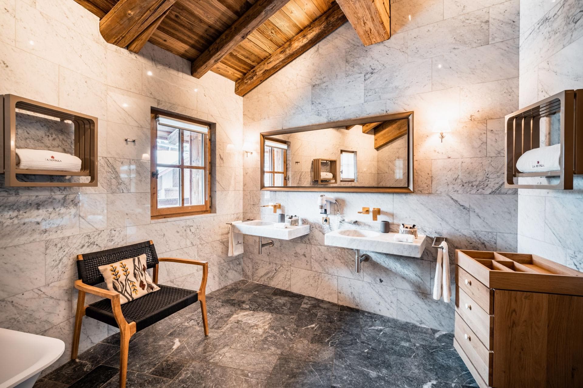 Bathroom with marble walls and dual wall-mounted vanity sinks