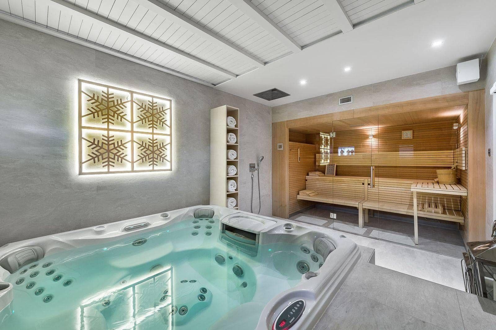 Indoor spa with multi-person hot tub, glass-fronted sauna, and rainfall shower