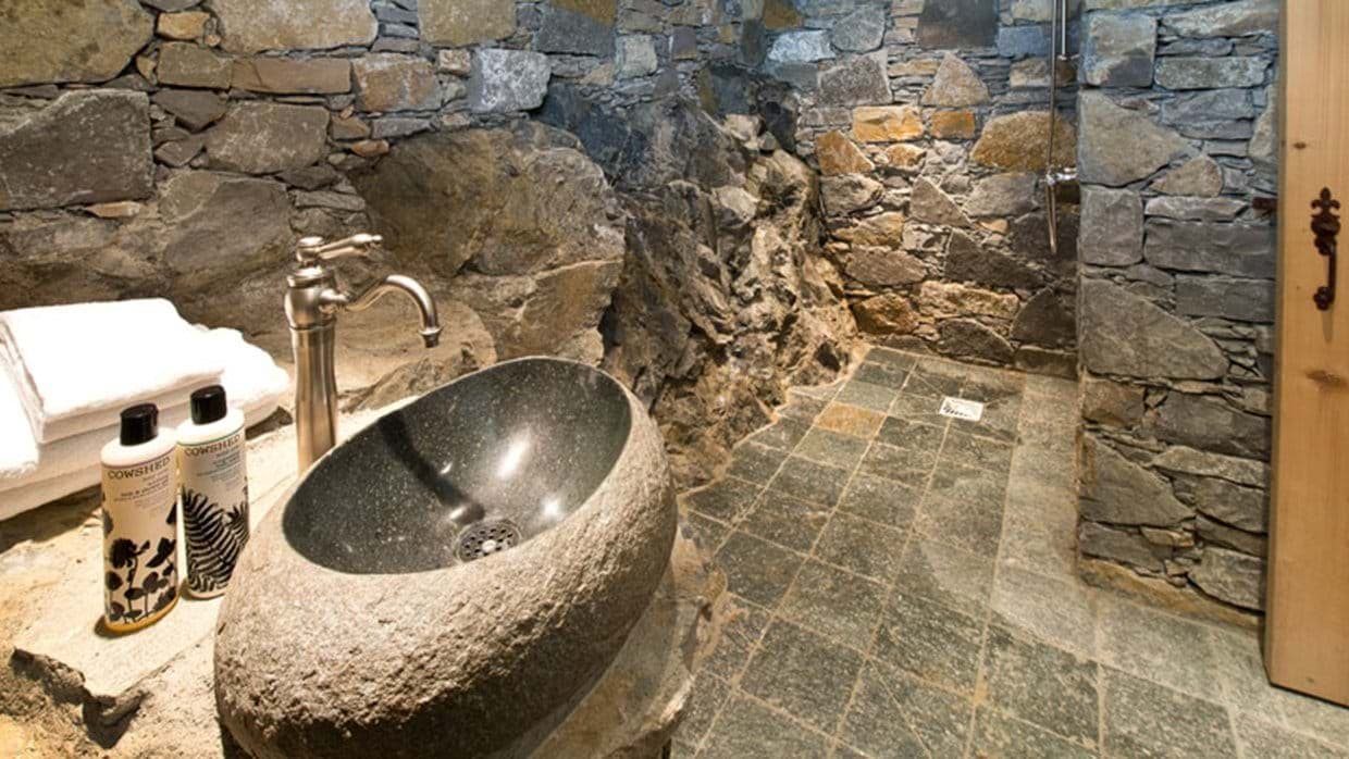 Bathroom with carved stone vessel sink and walk-in grotto shower