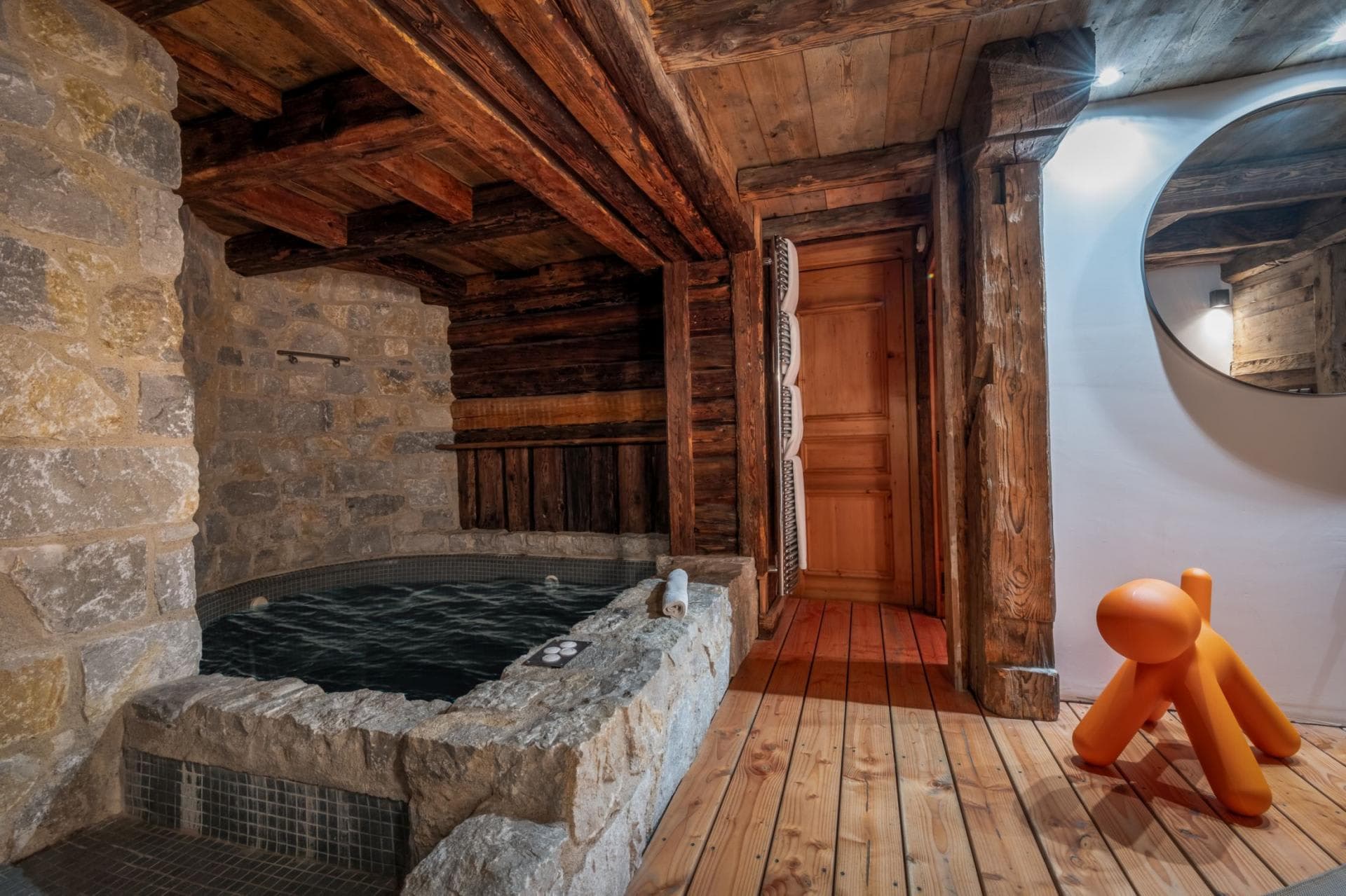 Indoor stone plunge pool with exposed timber beams and heated towel rack