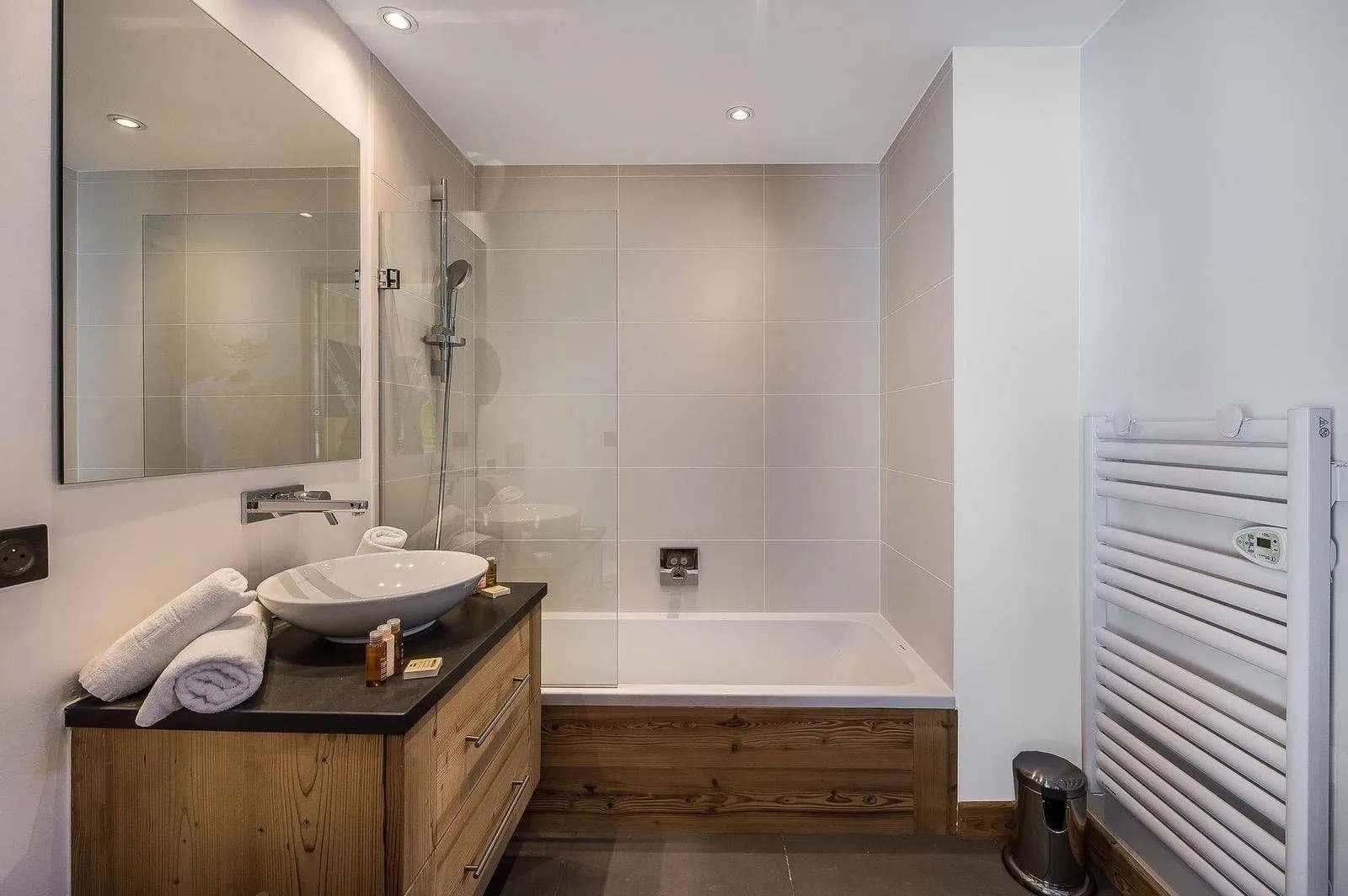 Bathroom with bathtub, double basins and heated towel rail