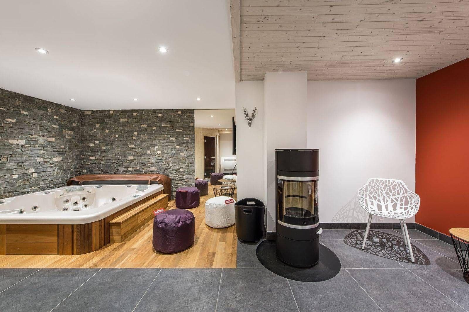 Indoor spa room with hot tub, wood-burning stove, and sauna access