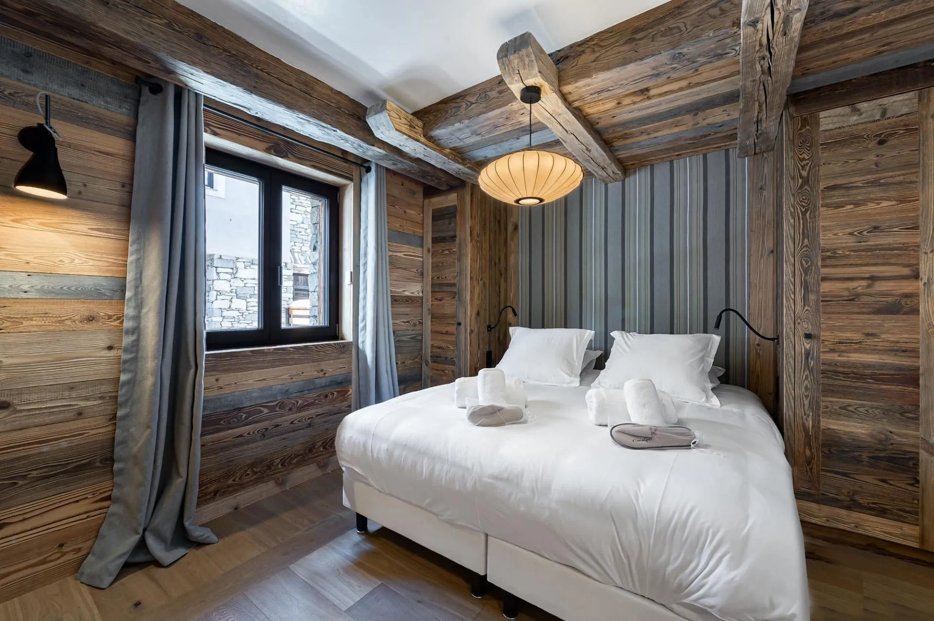 Double bedroom with timber walls and curtains