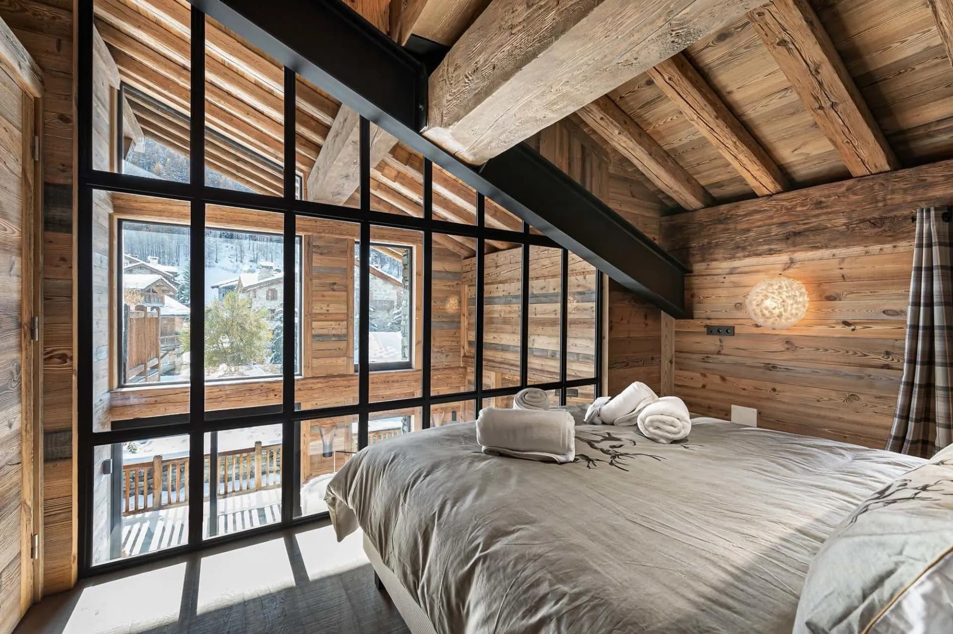 Mezzanine bedroom with glazed walls overlooking the village