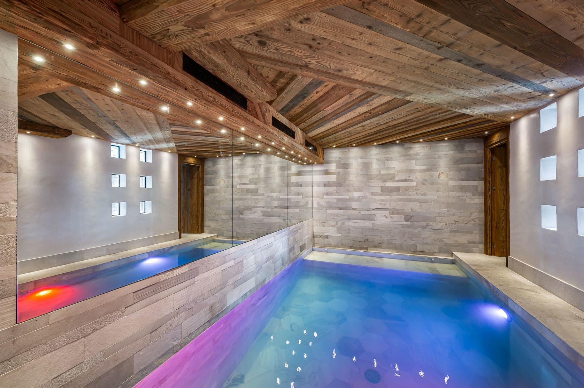 Indoor pool with mirrored wall and color-changing lighting