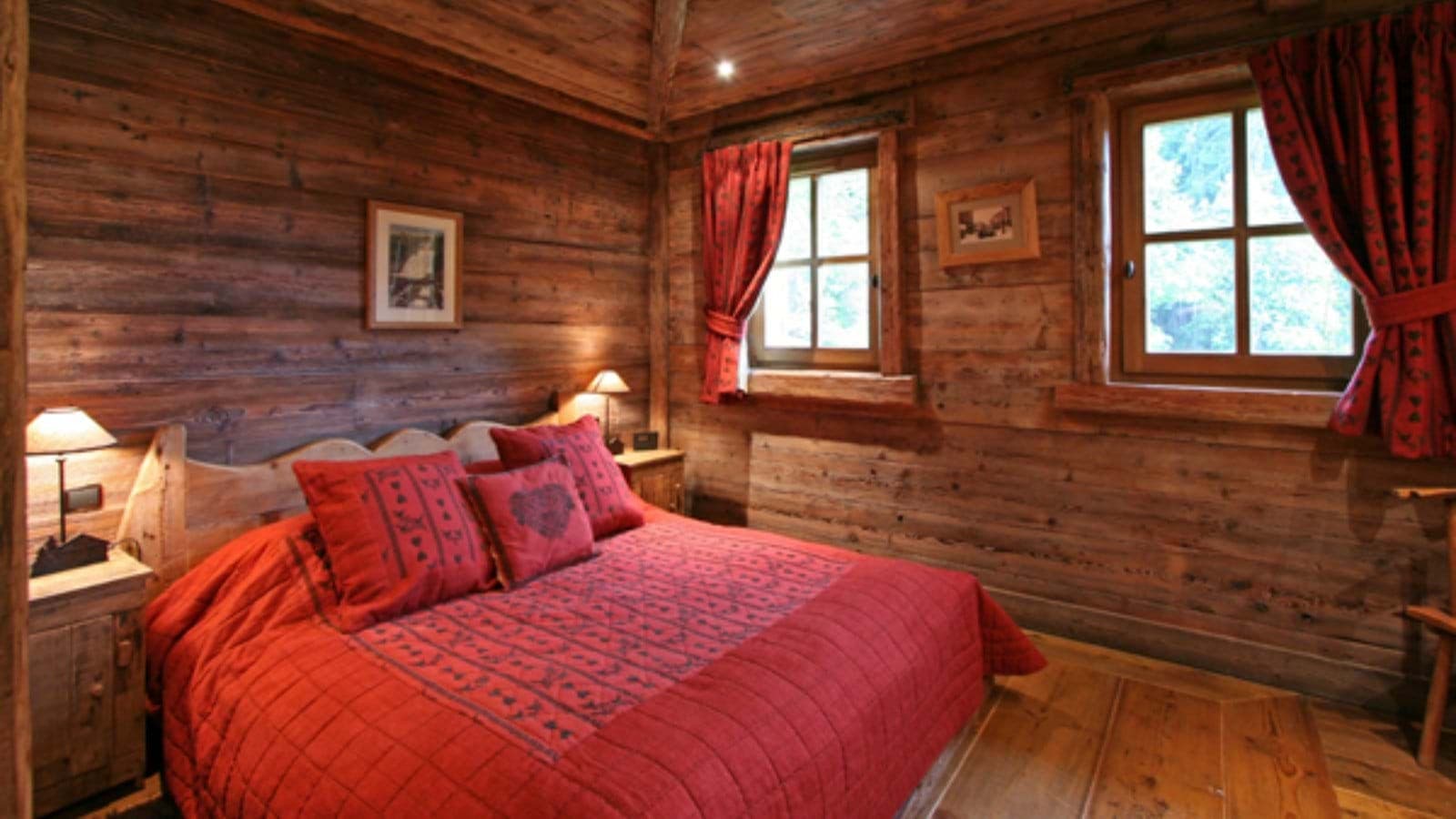 Log-walled bedroom with queen bed and dual bedside reading lamps