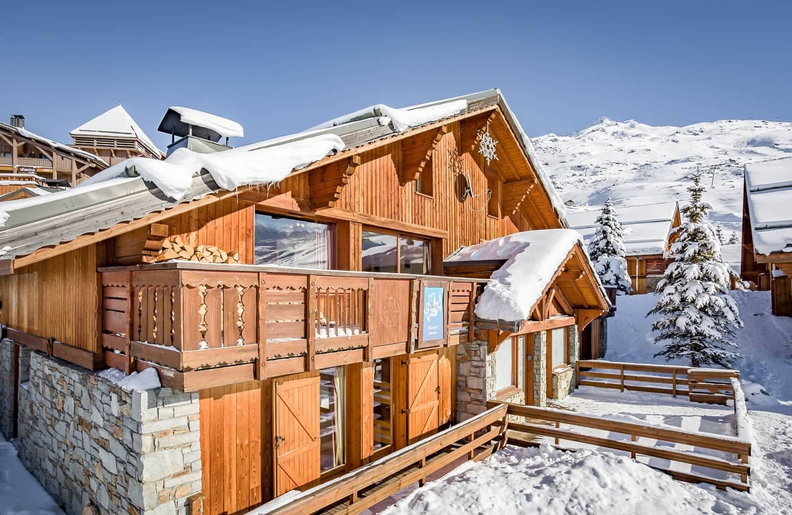 Chalet exterior with carved wood balcony and snowy mountain views