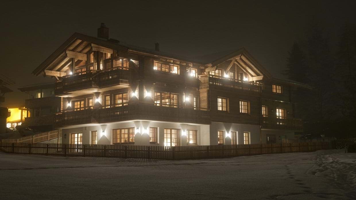 Chalet exterior at night with multiple private balconies and wraparound deck