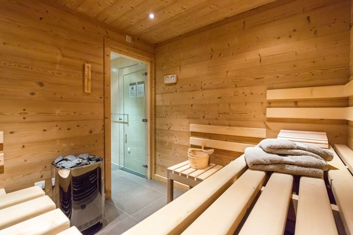 Private sauna with electric heater and adjacent walk-in shower