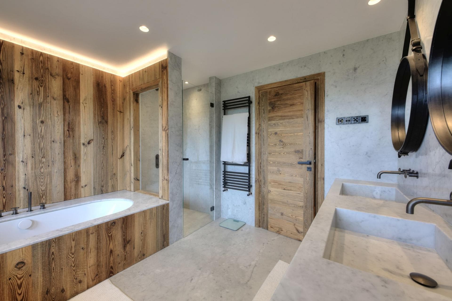 Bathroom with dual vanity, soaking tub, and heated towel rack
