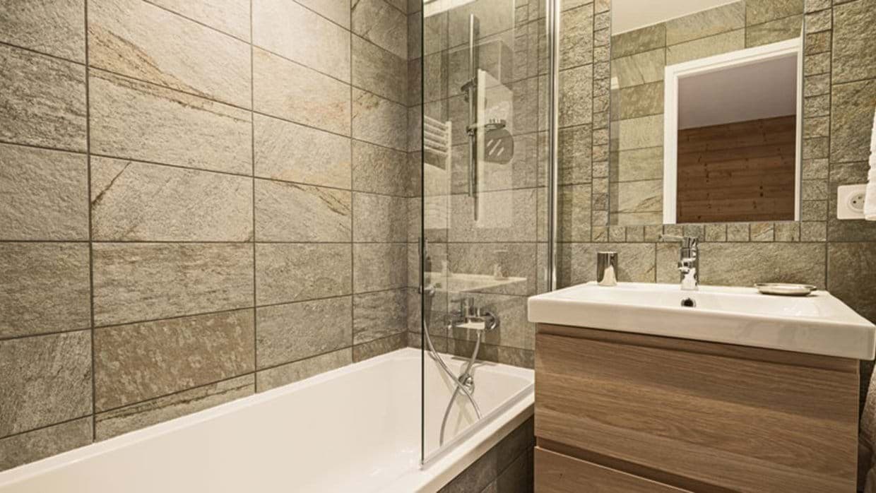 Bathroom with soaking tub, rainfall shower head, and slate tile