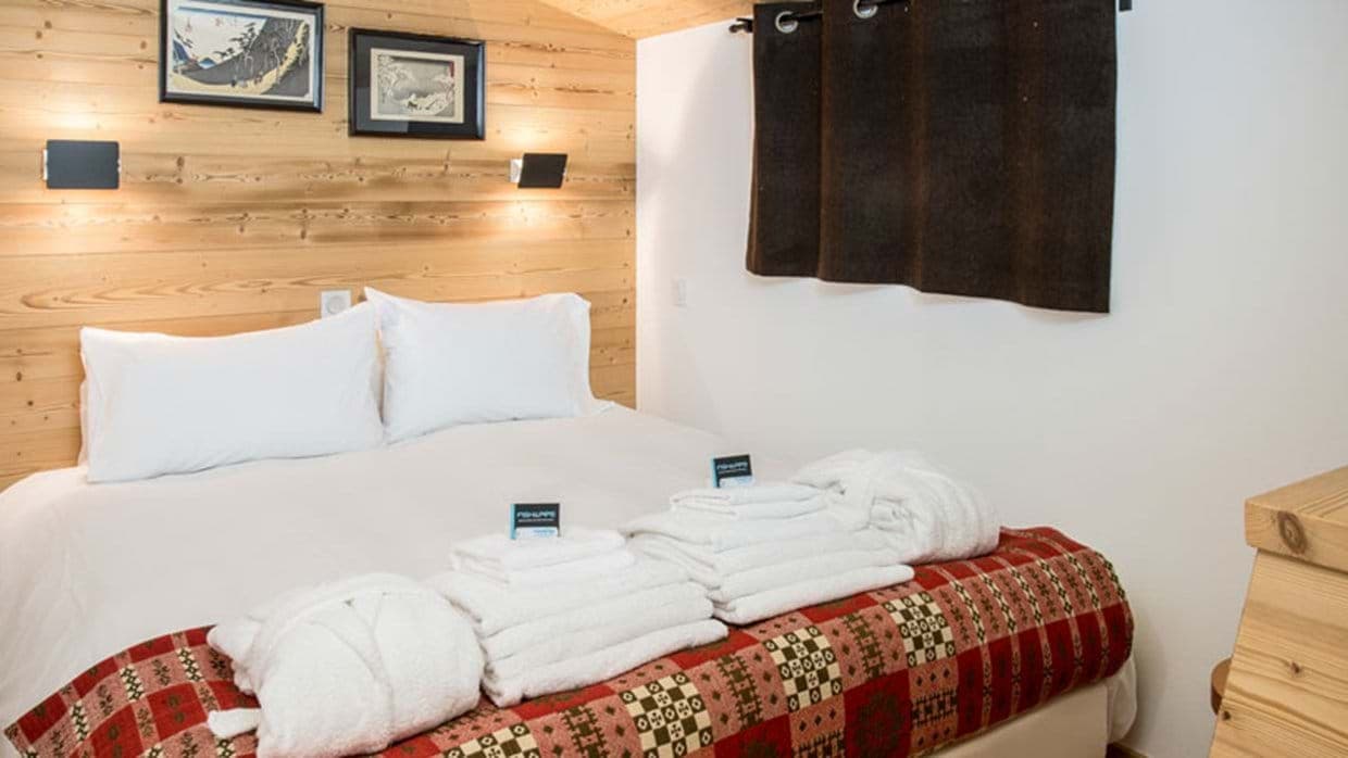Guest bedroom with queen bed and wood-paneled feature wall